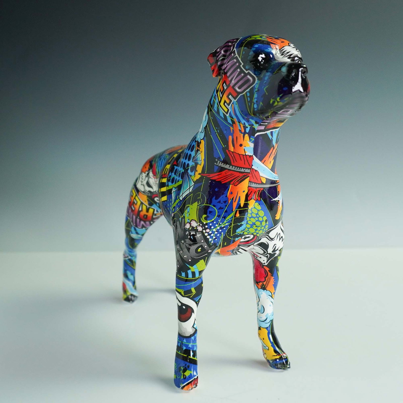 Pop Art Style Graffiti Dog Figurine, Rottweiler: Bold and vibrant pop art-style dog sculpture depicting a proud, alert Rottweiler. Crafted from a resin or composite base, the surface is wrapped in a glossy, decoupage-like collage featuring comic boo
