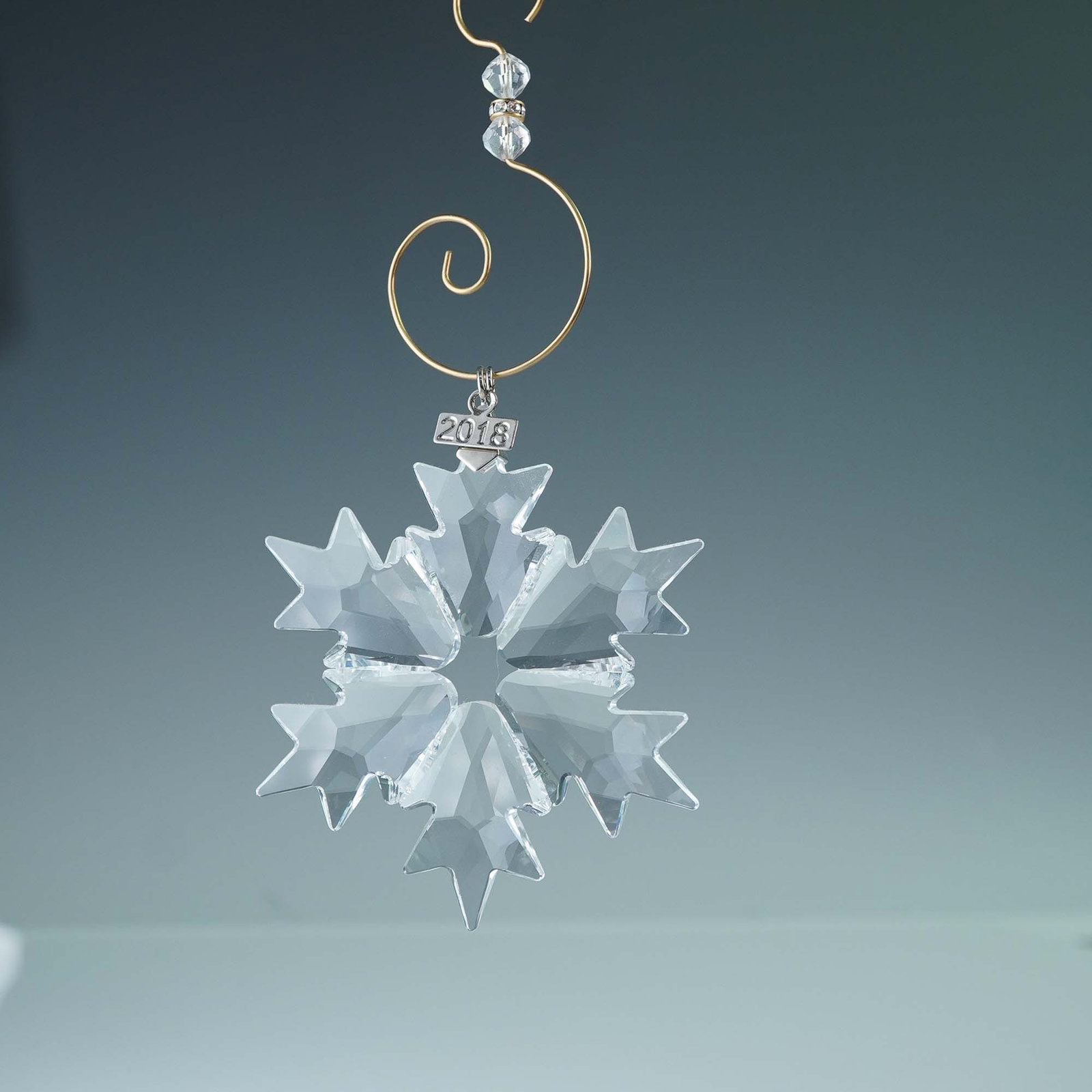 Swarovski Crystal Ornament, 2018 Christmas Snowflake 5301575: Swarovski Annual Edition Christmas ornament from 2018, featuring a finely faceted snowflake crafted with clear crystal cuts. Suspended by an ornament enhancer and accompanied by a polished metal tag e