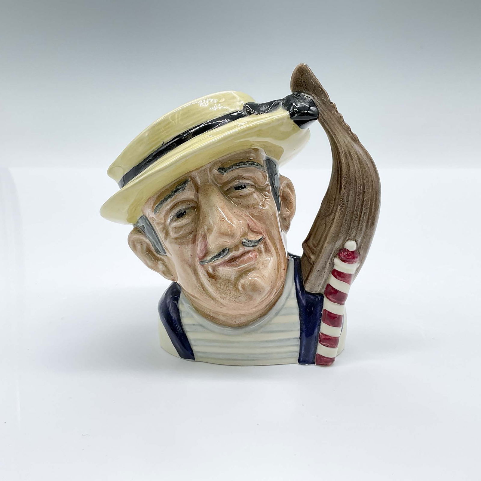 Royal Doulton Small Character Jug, Gondolier D6592: Hand decorated and hand painted figural jug of a Venetian boatman. The handle is formed as a gondola. Royal Doulton backstamp. Artist: David B. Biggs Issued: 1964-1969 Dimensions: 4.25"L x 3.25"W x 4.