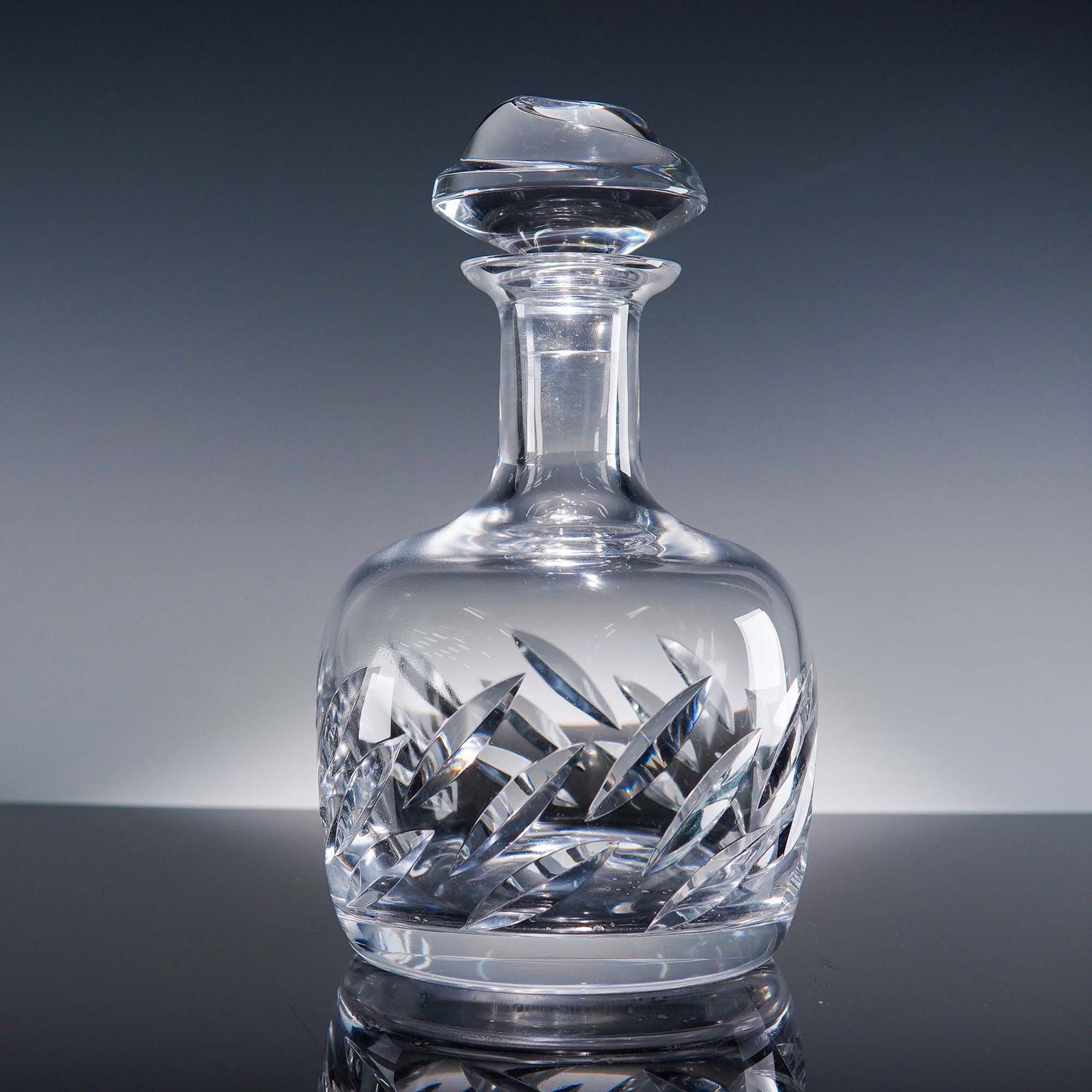 Lalique Crystal Artois Decanter with Stopper: Lalique France crystal decanter in the Artois pattern, featuring a striking leaf motif expertly cut around the body, paired with a heavy, sculptural stopper. The clear crystal showcases Lalique's sign