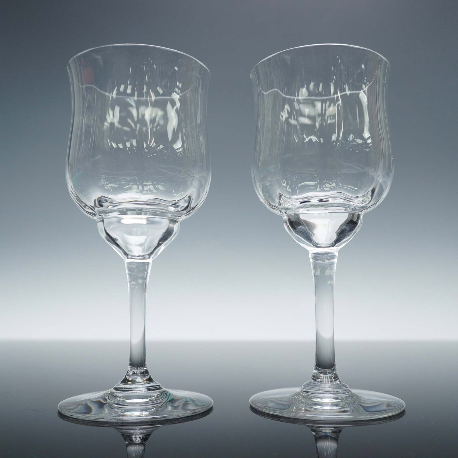 2pc Baccarat Crystal Wine Glasses, Capri: Pair of clear crystal wine glasses, each showcasing a slightly flared tulip shaped bowl with a rounded lower section and smooth transition to the slender stem and wide circular foot. These pair of win