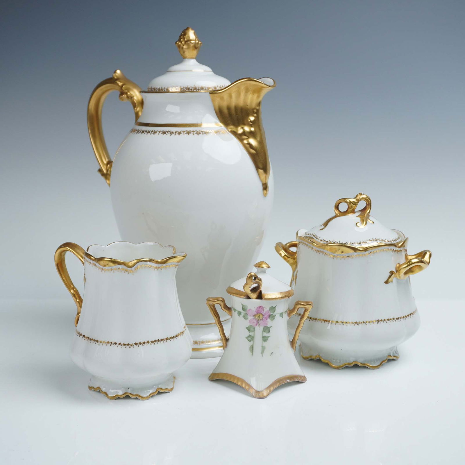 4pc French Porcelain Tea Set: This refined 4-piece French porcelain tea set includes two pieces marked Elite Works Limoges France, one piece stamped D & C France, and one unmarked but clearly crafted in the same elegant style. Eac