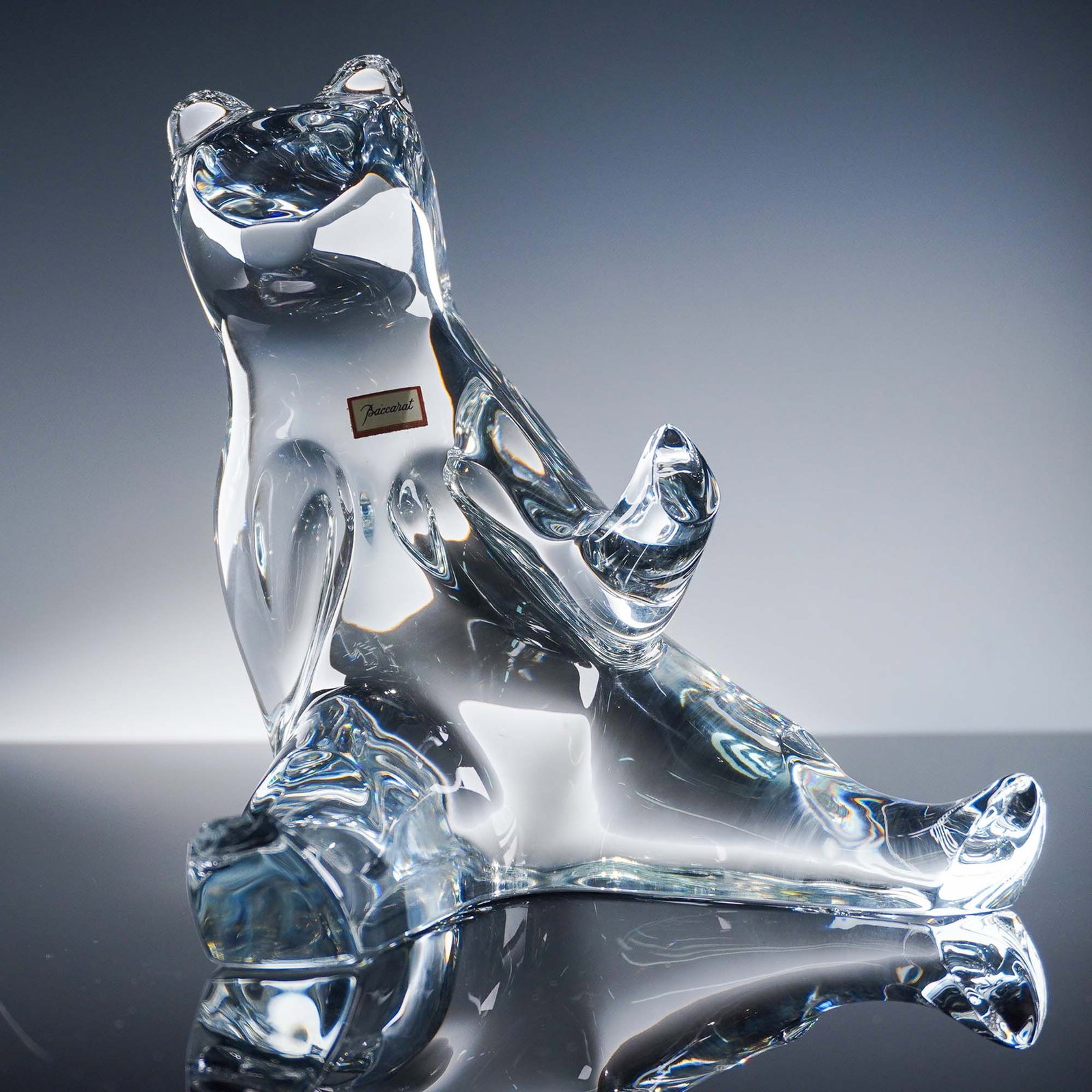 Baccarat Crystal Bear Sculpture: Baccarat crystal sculpture of a seated bear with smooth contours and expressive posture, crafted in clear French crystal. The original Baccarat label is affixed to the chest and the backstamp on the b