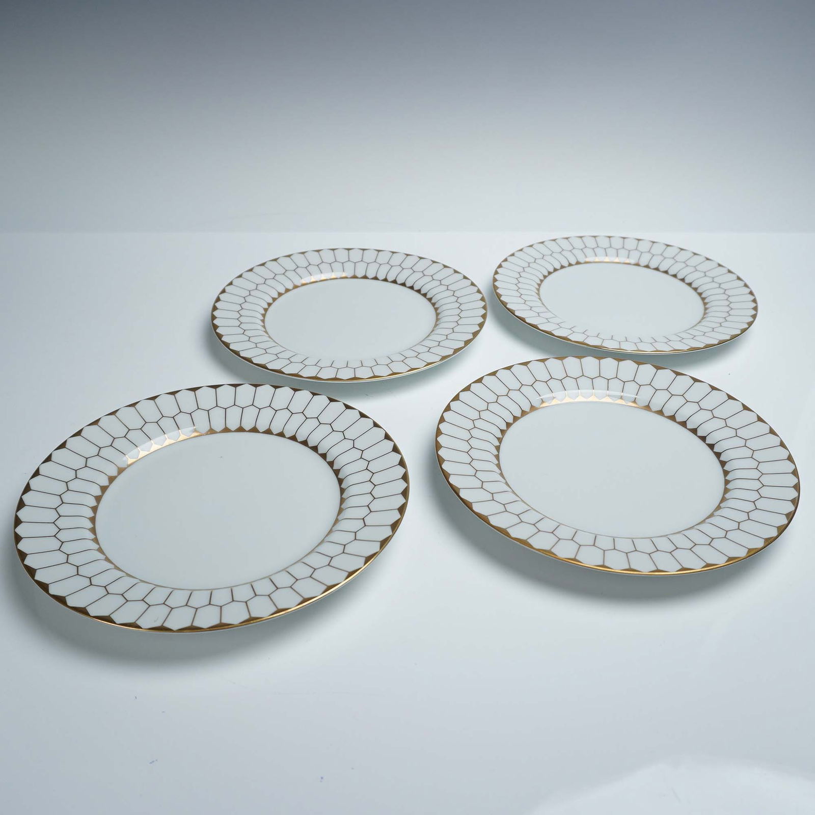 4pc Fitz and Floyd Contrepoint Fine Porcelain Dessert Plates: A set of four fine porcelain dessert or salad plates by Fitz and Floyd in the Contrepoint pattern. Each 7.5-inch plate features a clean white ground with a wide border of stylized gold honeycomb or ne
