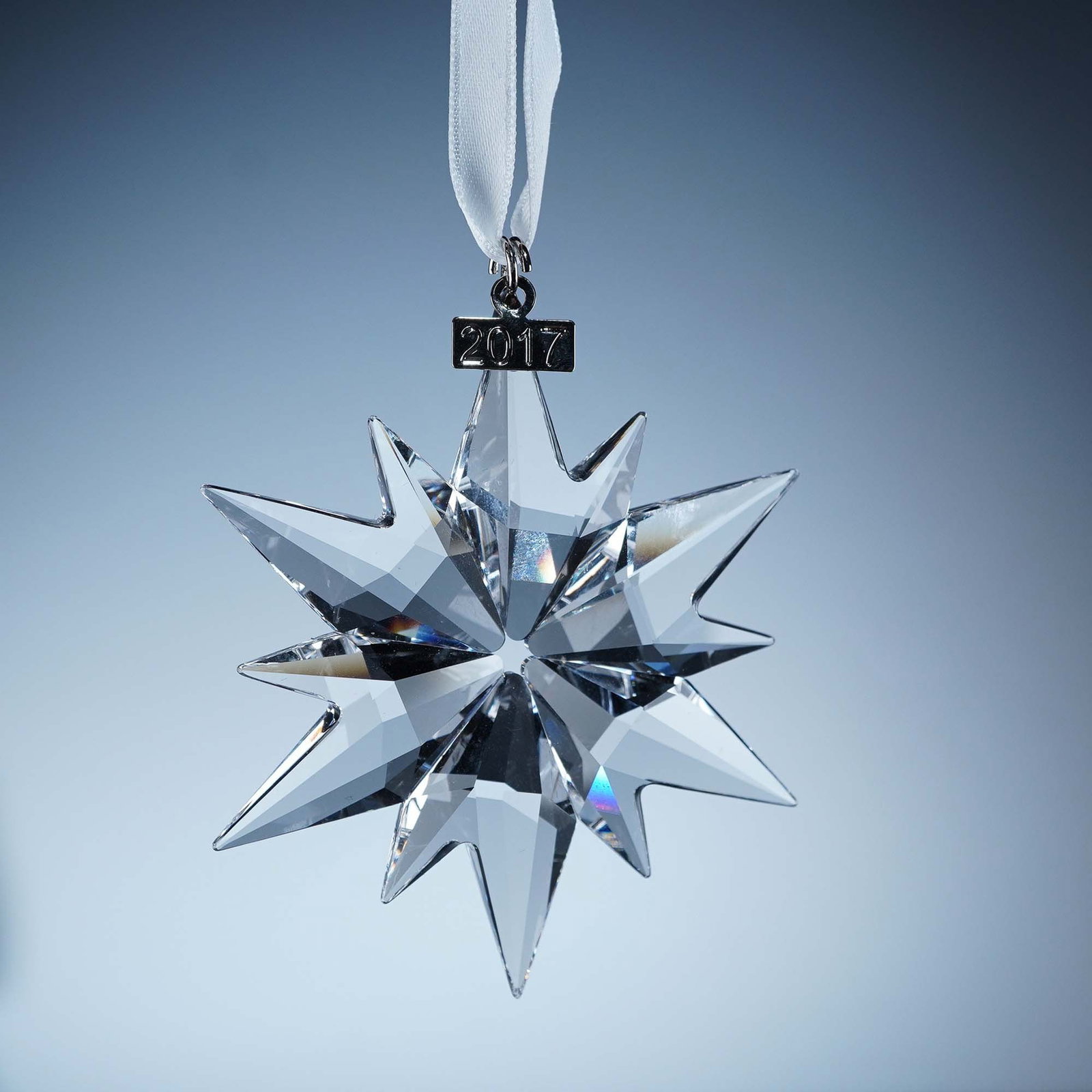 Swarovski Crystal Ornament, 2017 Christmas: This retired Swarovski 2017 Annual Edition Christmas Ornament showcases a brilliantly cut 12-point faceted clear crystal star, enhanced by a 2017-etched metal tag. Suspended from a white satin ribbon 