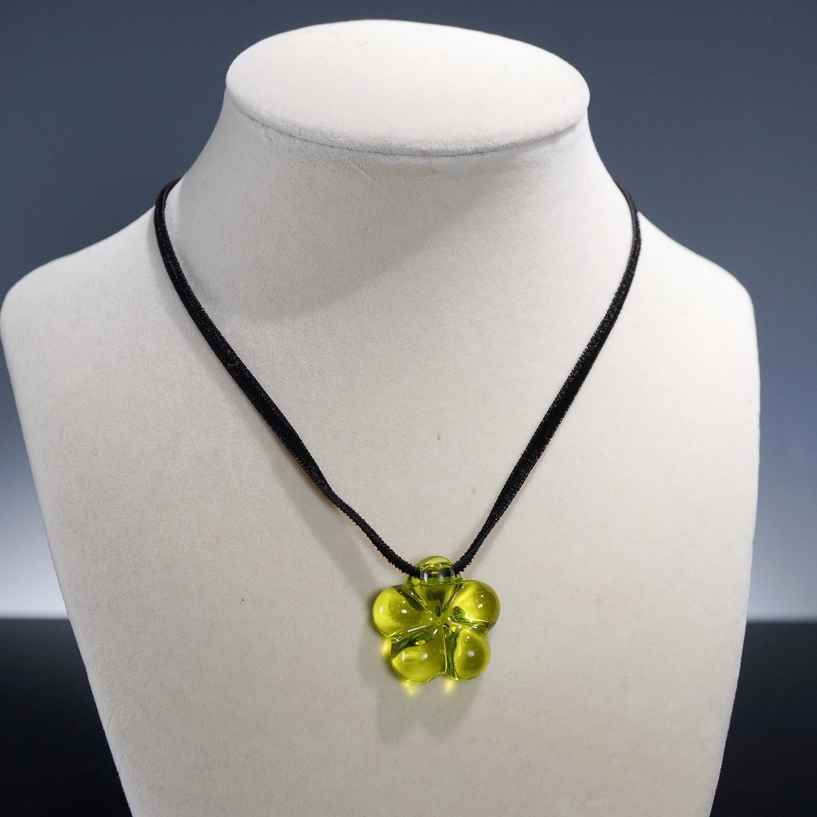 Baccarat Crystal Lili Olivine Choker: Elegant Baccarat Lili choker featuring an olivine green crystal flower pendant suspended on a sleek black cord. The floral design showcases sculptural petals in finely crafted crystal with a soft shee