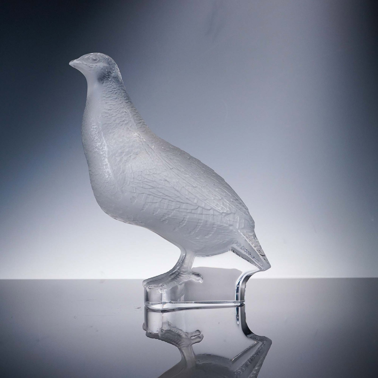 Lalique Crystal Figurine, Partridge: A frosted and clear figure in the form of a partridge. Features finely detailed feathering in frosted crystal with a smooth clear base. Lalique etched backstamp. Dimensions: 5.25"L x 3.25"W x 7"H Coun