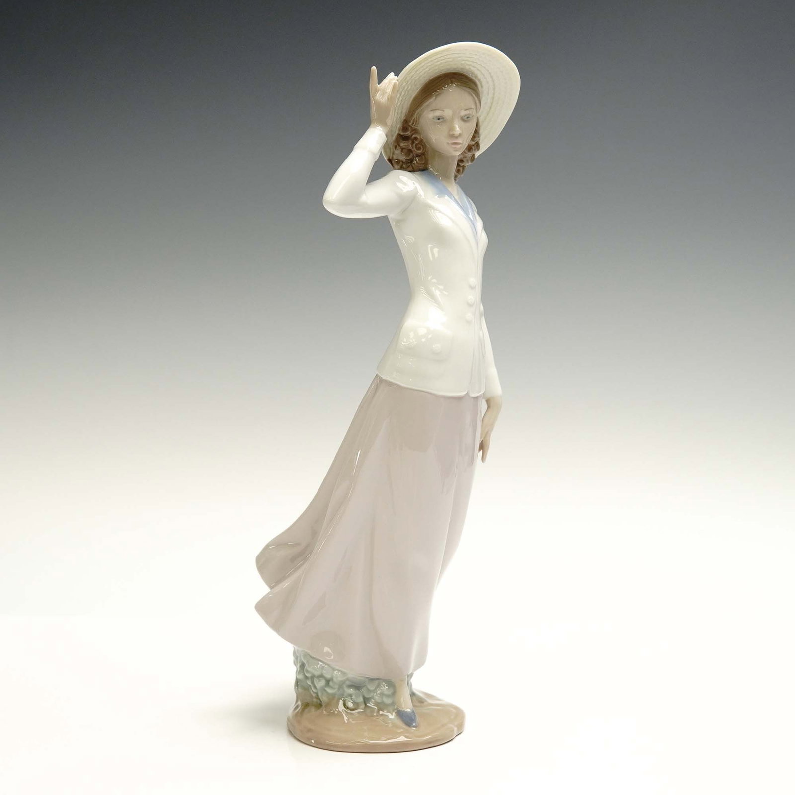 Lladro Porcelain Figurine, Breezy Afternoon 01005682: This refined Lladro porcelain figurine, Breezy Afternoon (01005682), beautifully depicts a graceful young woman in motion, lightly holding the brim of her straw hat against the breeze. Designed by scu