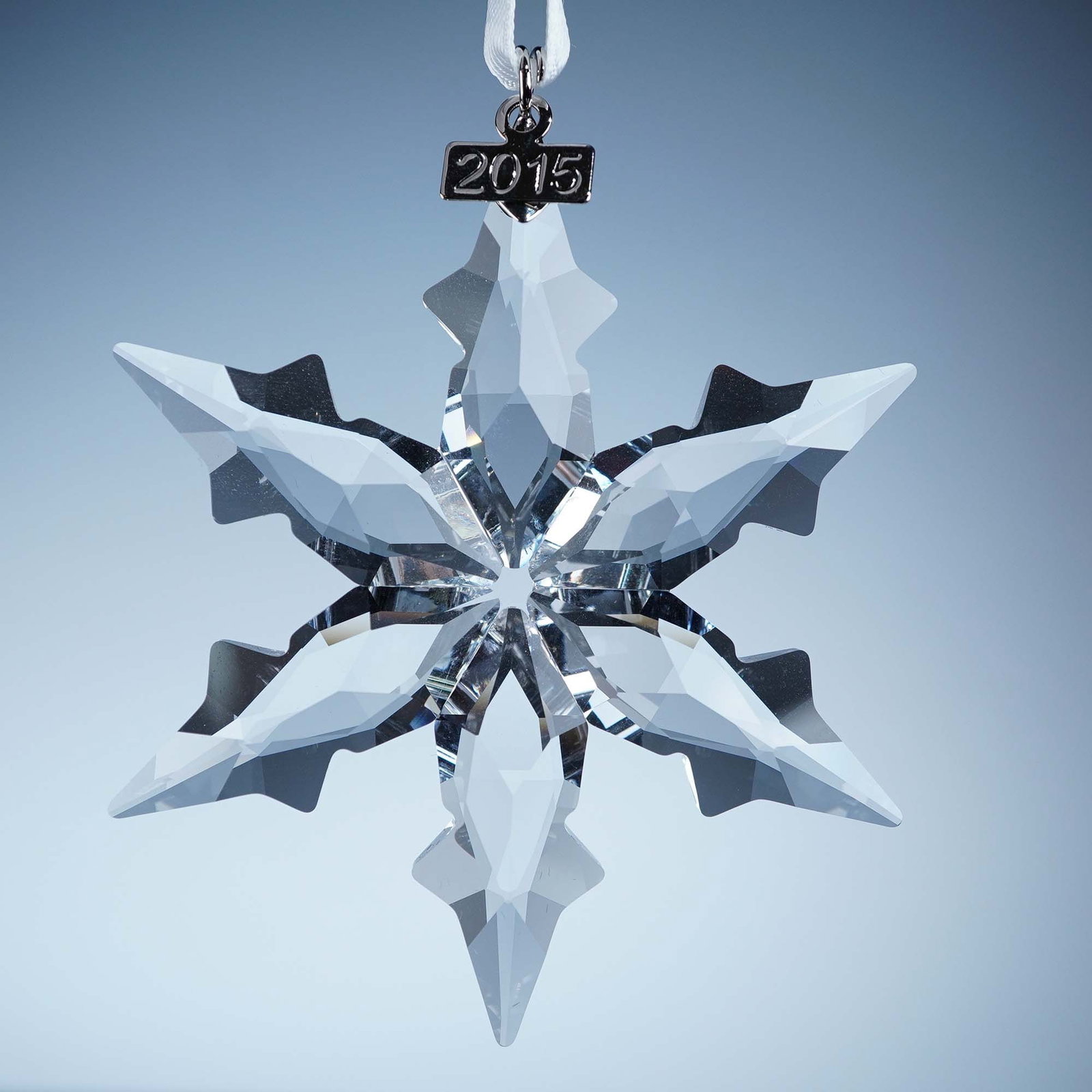 Swarovski Crystal Ornament, 2015 Christmas: This retired Swarovski 2015 Annual Edition Christmas Ornament features a radiant 12-point faceted clear crystal star and a 2015-etched metal tag. The original white satin ribbon and triangular blue Sw