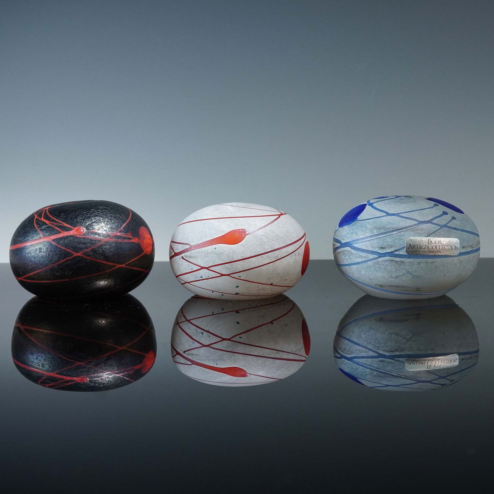 3pc Boda Artist Collection Glass paperweights by Bertil Vallien: Group of three Swedish art glass paperweights from the Boda Artist Collection, designed and signed by renowned glass artist Bertil Vallien. Each piece is crafted in a rounded organic form with matte,