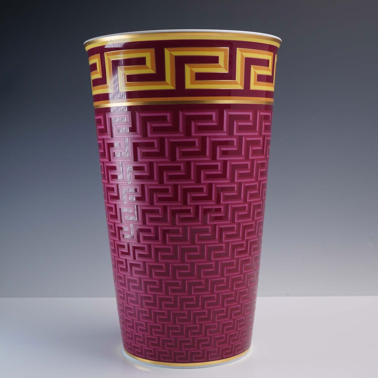 Versace Rosenthal Medusa Mezzo Vase: An opulent Versace for Rosenthal porcelain vase from the coveted Medusa Mezzo collection, standing an impressive 11.5"H. The vase features a striking geometric pattern in rich magenta with golden Gree