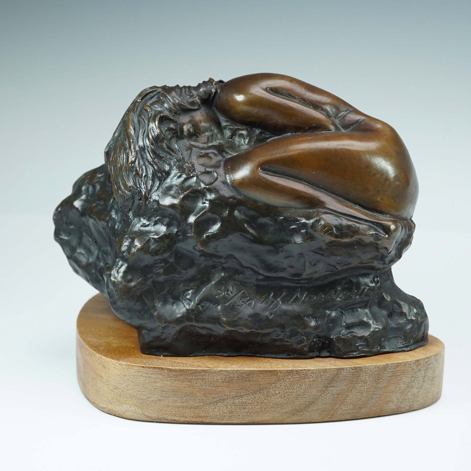 Hueberto Maestes (American, b.1960) Bronze Sleeping Nude Sculpture: Limited edition bronze sculpture depicting a sleeping nude female figure curled against a textured, organic backdrop. The composition blends polished and rugged surfaces for dramatic contrast and emot