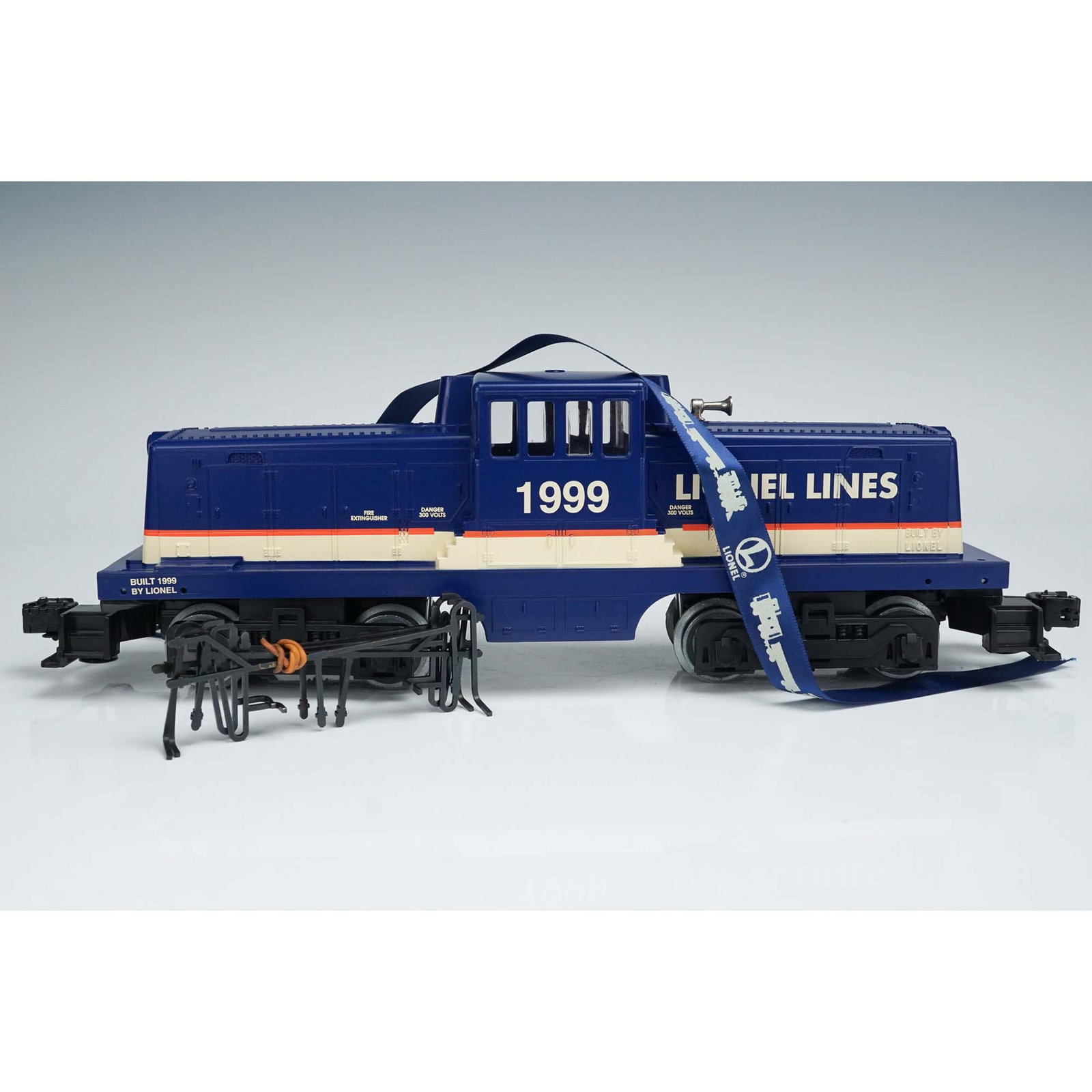 Lionel Lines Diesel Locomotive, 1999 Blue Switcher: Lionel Lines 1999 Diesel Locomotive, presented in classic blue with cream and red detailing, marked Built 1999 by Lionel. This O-gauge switcher locomotive features dual powered trucks, visible motor a