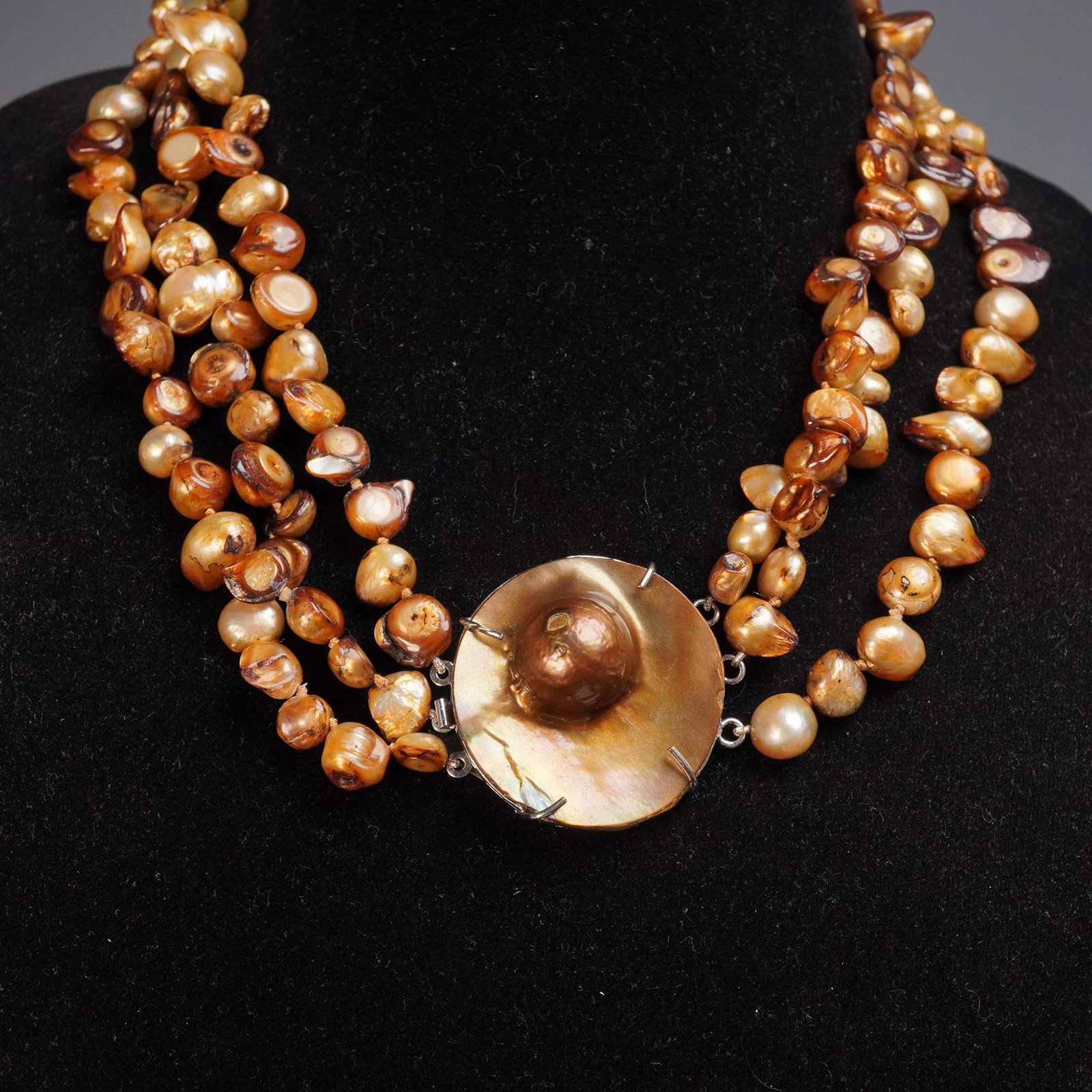 Austrian Iridescent Faux Pearl Necklace: This striking necklace features three graduated strands of golden cultured faux pearls in baroque and irregular forms, displaying rich caramel, honey, and amber hues with natural iridescence. At its c