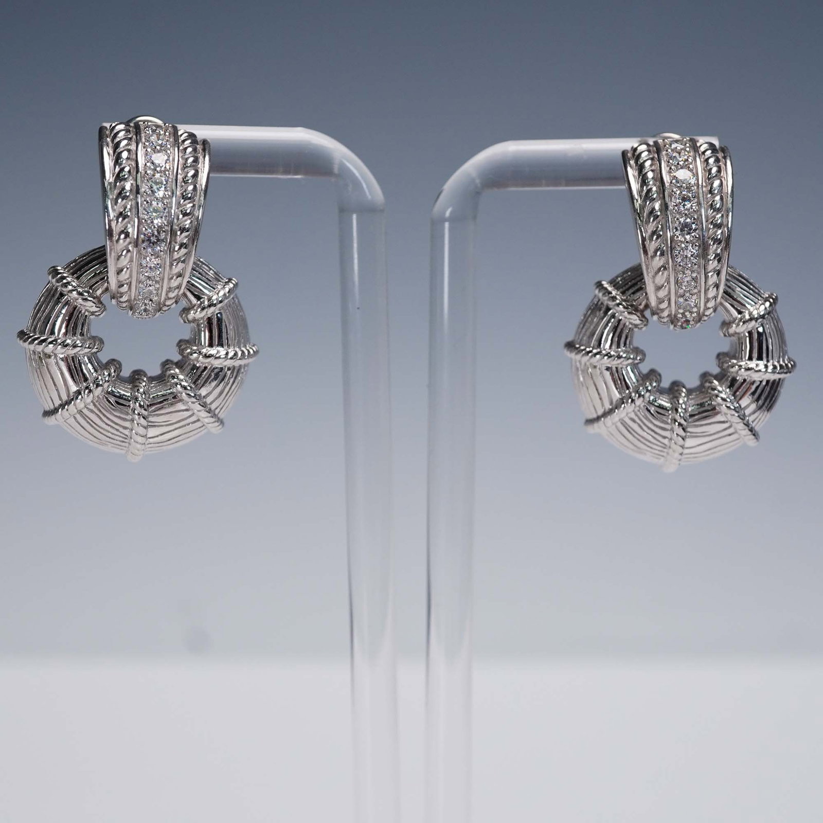 Judith Ripka Sterling Hoop Earrings with CZ Accents: Pair of designer sterling silver hoop earrings by Judith Ripka, featuring a sculpted ribbed and rope-wrapped design with inset cubic zirconia accents. Each is marked 925, Judith Ripka, Thailand, CZ on