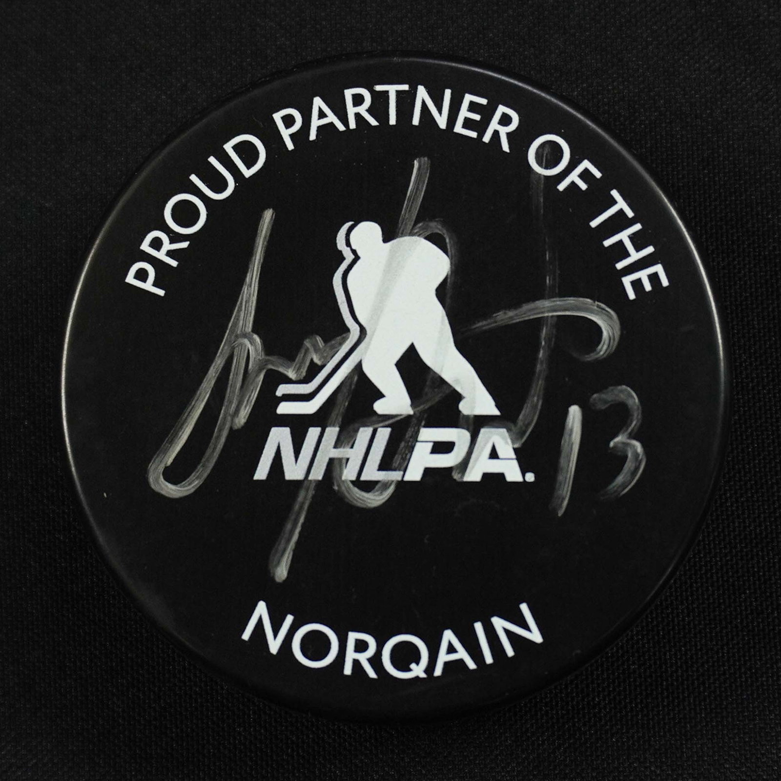 Signed Sam Reinhart NHLPA Norqain Hockey Puck: Official NHLPA Norqain hockey puck autographed by Sam Reinhart, featuring the NHL Players' Association logo and branding from Norqain, the official watch partner of the NHLPA. The puck is boldly signe