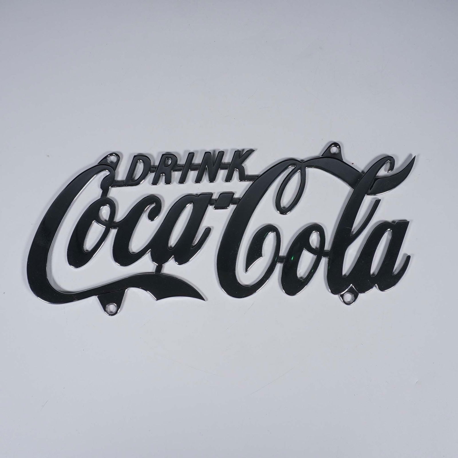 Coca-Cola Metal License Plate: Coca-Cola metal license plate in a polished chrome-style finish. Dated 1998 and marked on the reverse with trademark and copyright information from The Coca-Cola Company, this piece is shaped to match