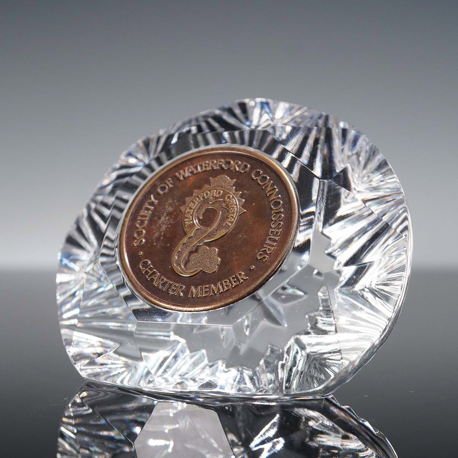 Waterford Crystal Charter Member Society Paperweight: Faceted clear crystal paperweight by Waterford, featuring an embedded bronze-toned medallion inscribed with "Society of Waterford Connoisseurs" and "Charter Member." The central motif includes a class