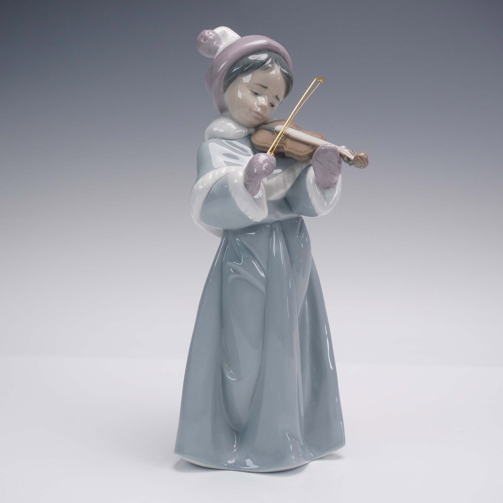 Lladro Porcelain Figurine 6534 Girl With Violin, with Original Box: This Lladro porcelain figurine, model number 6534, depicts a young girl gracefully playing the violin, captured mid-performance with delicate detail and emotive expression. Crafted in Spain, the glaze