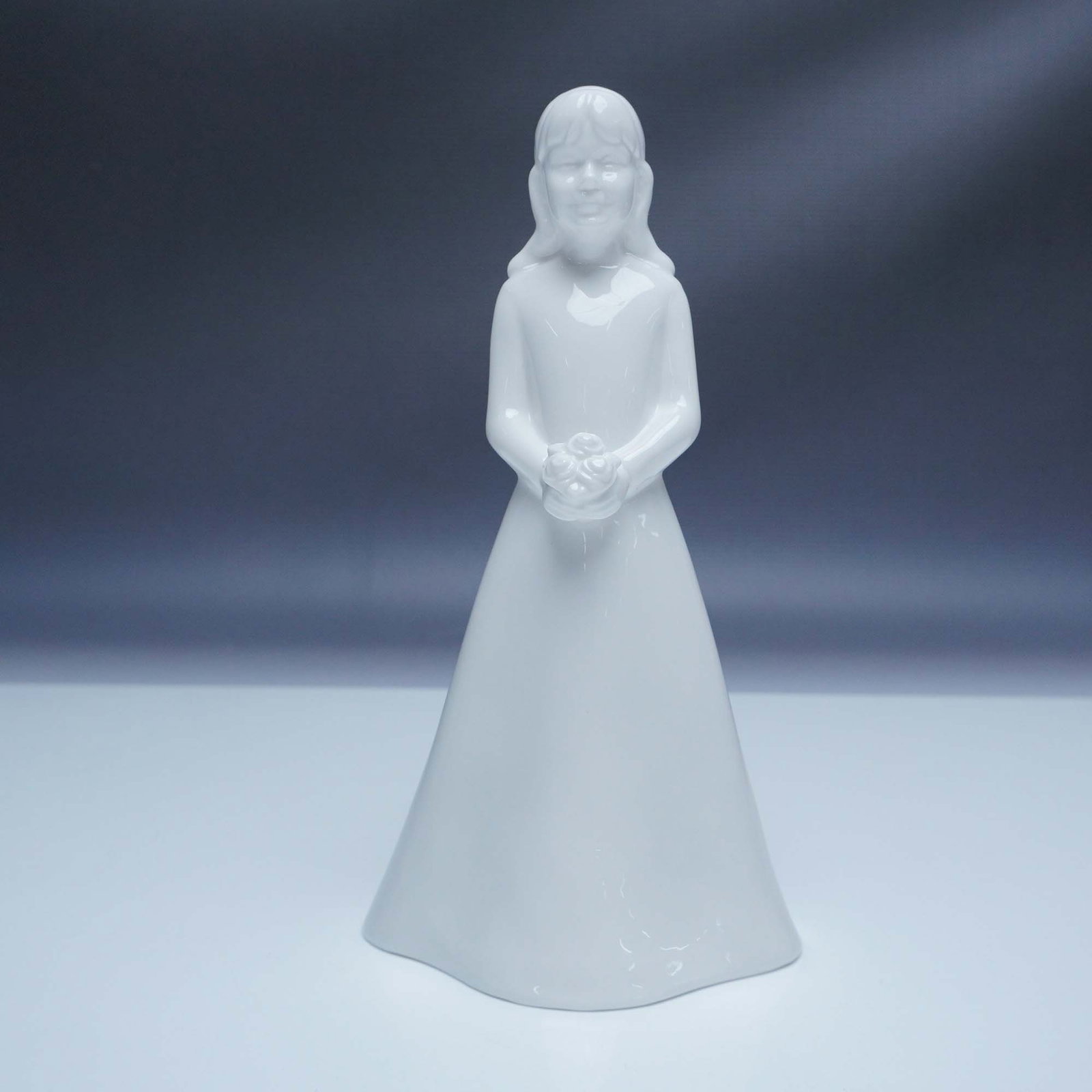 Coalport Moments Figurine, The Bridesmaid: Elegant Coalport bone china figurine from the Moments collection. This all-white piece features a young bridesmaid in a flowing gown, holding a delicate bouquet. Crafted with fine attention to detail,