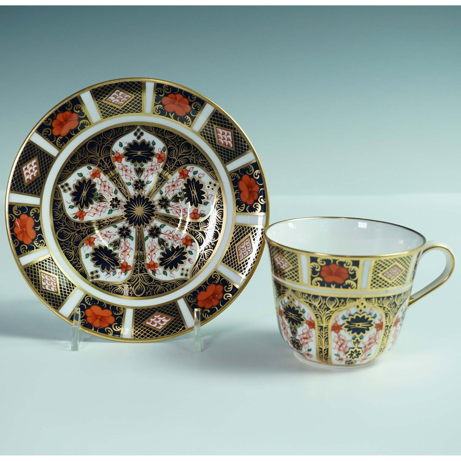2pc Royal Crown Derby Bone China Old Imari Teacup and Saucer Set: A fine Royal Crown Derby porcelain teacup and saucer in the iconic Old Imari pattern 1128. This richly decorated set features a bold palette of cobalt blue, iron red, and lavish 22-karat gold accents 