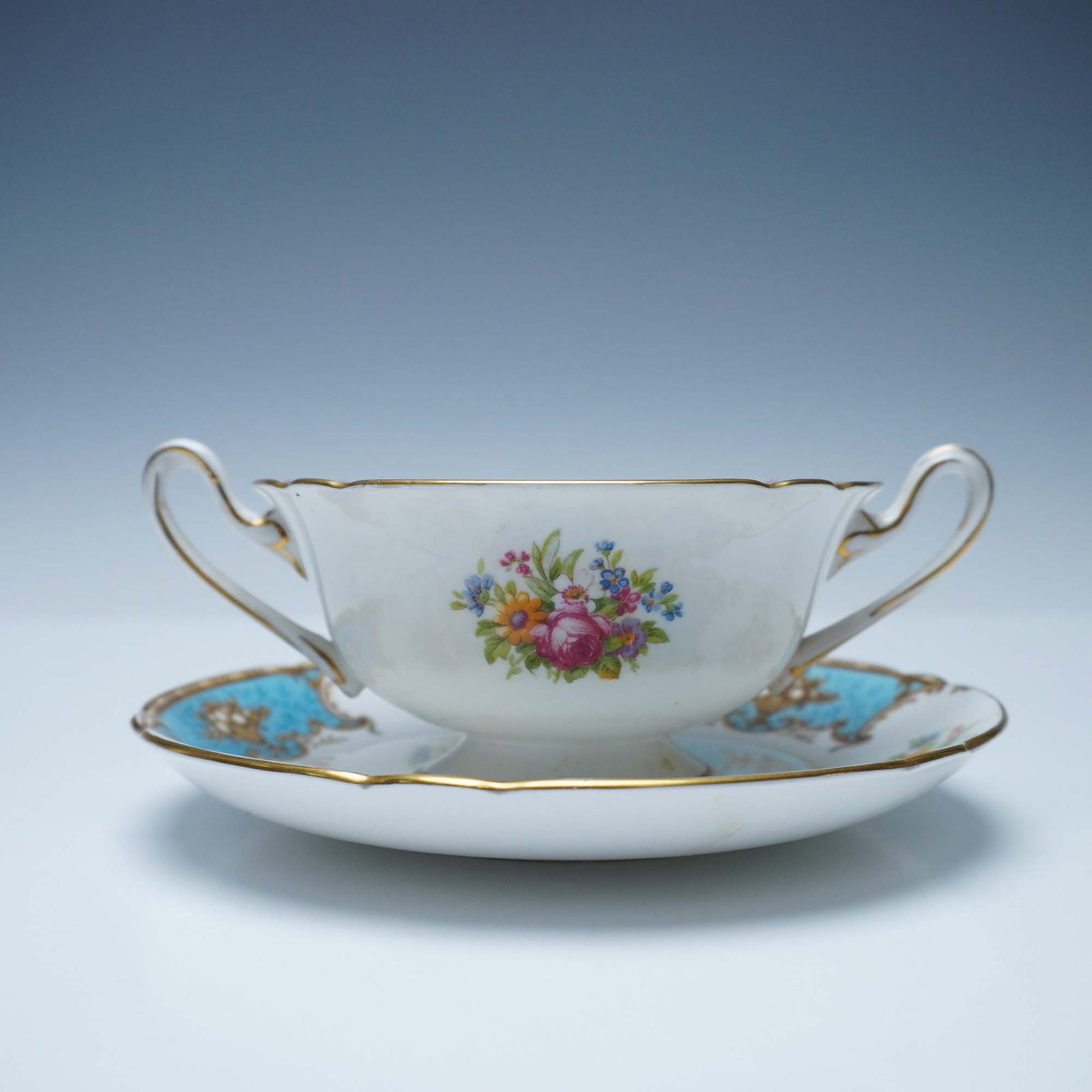 2pc Shelley Bone China Soup Cup and Saucer, Duchess 13403: A stunning Shelley Duchess pattern 13403 cream soup cup and saucer set, crafted from fine bone china. This exquisite set features a central floral bouquet with vibrant roses and wildflowers, complemen