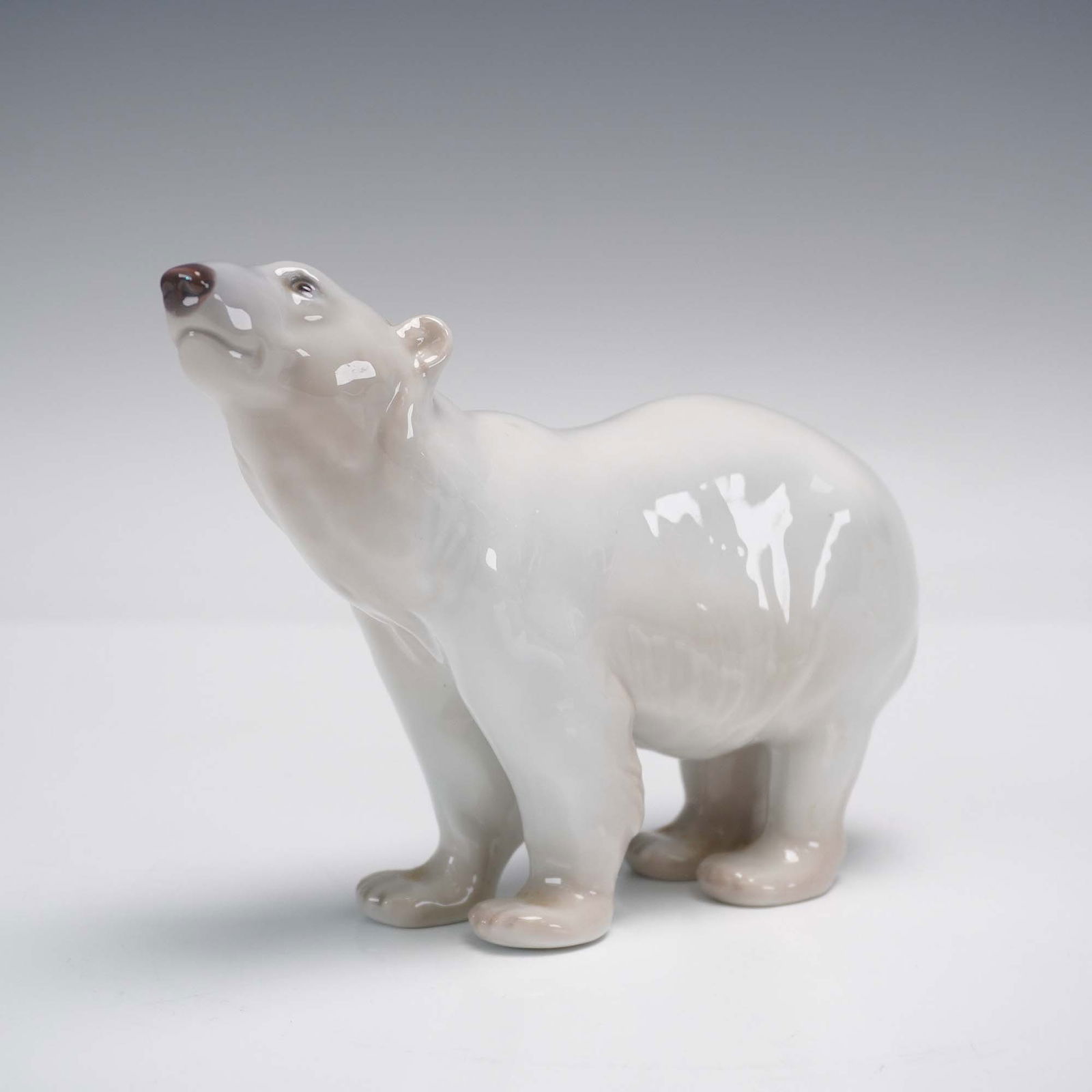 Bing & Grondahl Porcelain Figurine, Polar Bear: Bing & Grondahl porcelain figurine features a polar bear standing alert with its head raised. Finished in a glossy white glaze with naturalistic detail, and marked on the underside with the B&G hallma