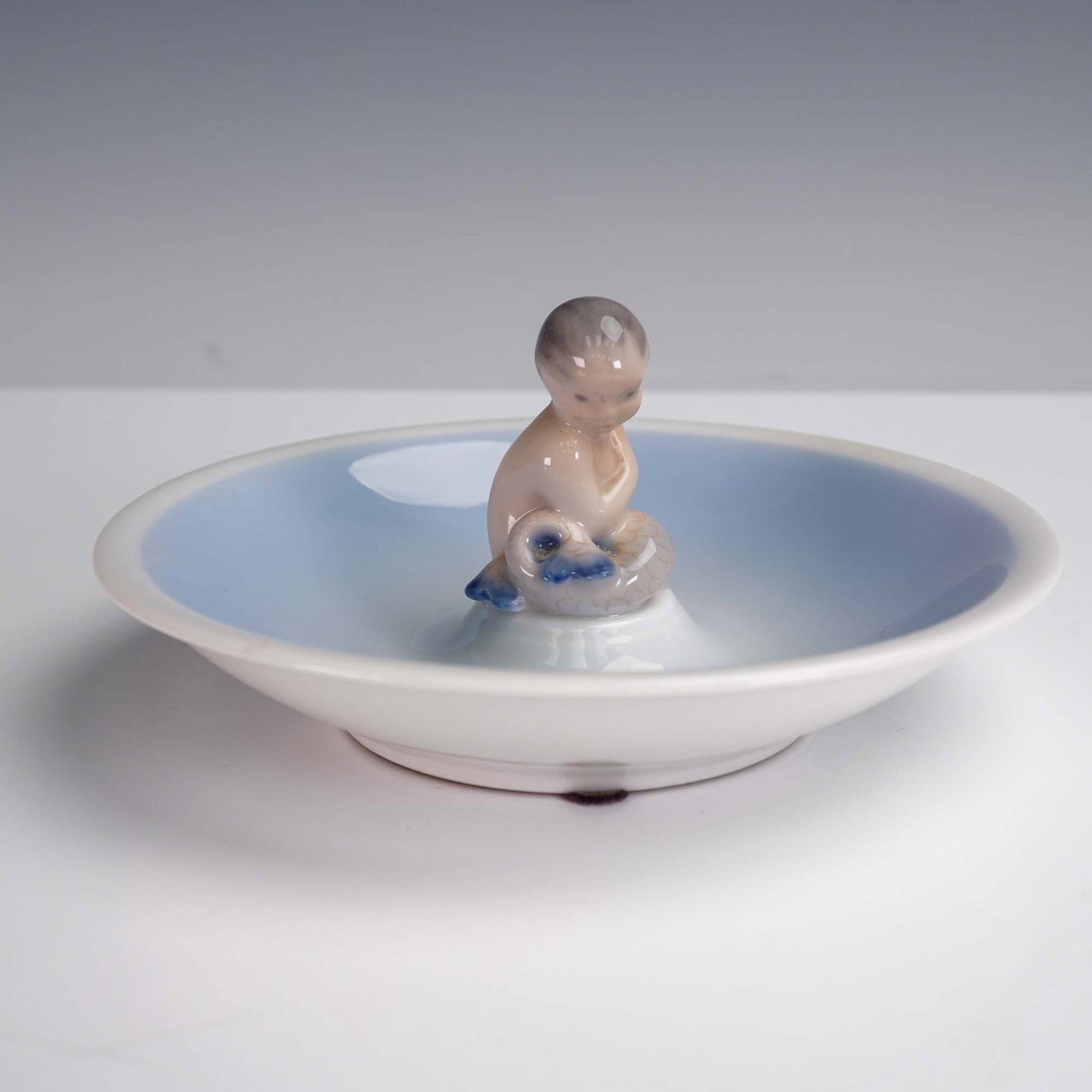 Royal Copenhagen Porcelain Figurine Dish, Mermaid 3231: This graceful porcelain dish by Royal Copenhagen features a serene mermaid figure seated at the center, finished in soft pastel glazes. Model number 3231, the piece reflects the Danish porcelain tradi