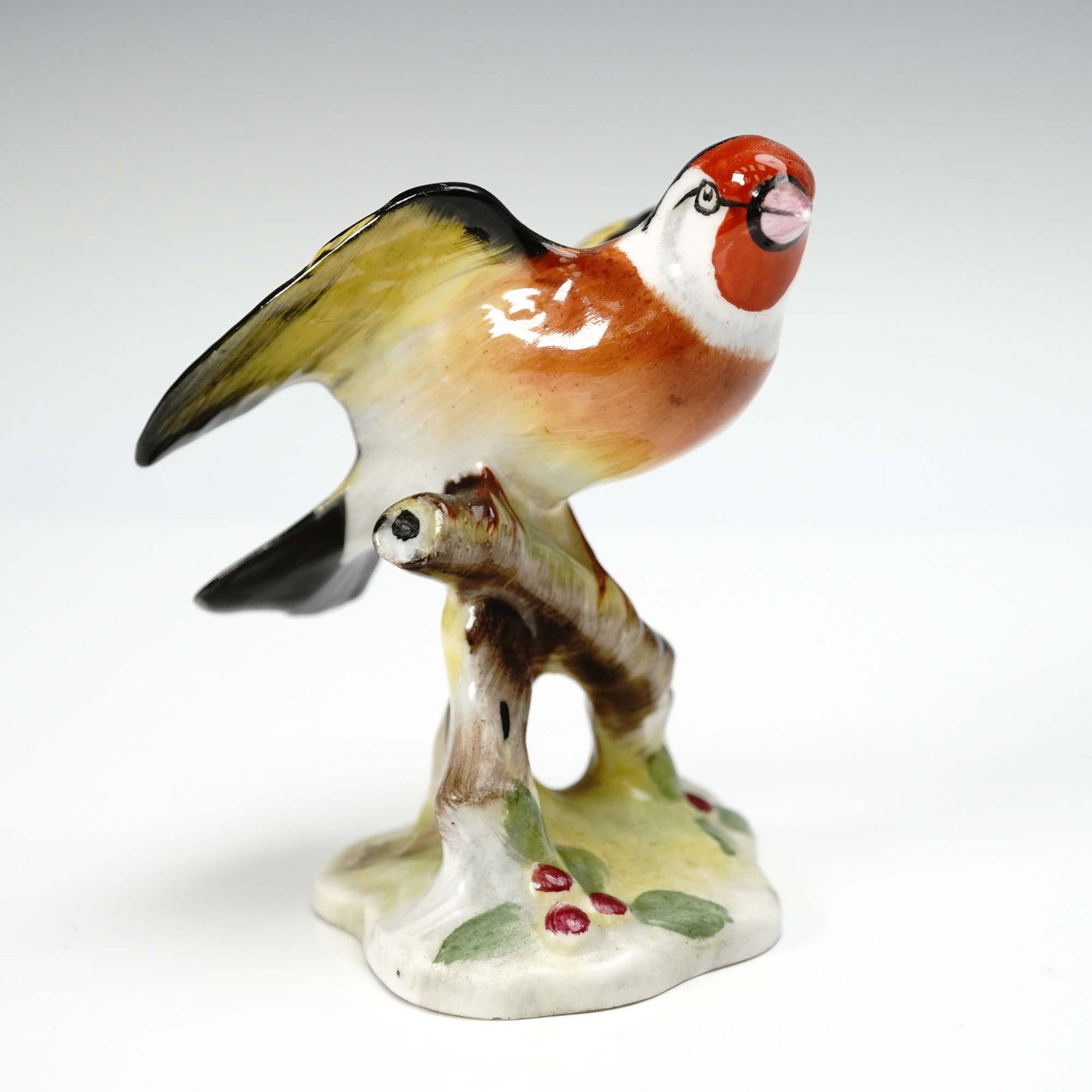 Royal Doulton Bone China Figurine, Goldfinch Bird: Charming hand-painted bone china figurine by Royal Doulton, depicting a vibrant goldfinch perched on a naturalistic base with berries and leaves. Finished in rich glazes with delicate feather detailin