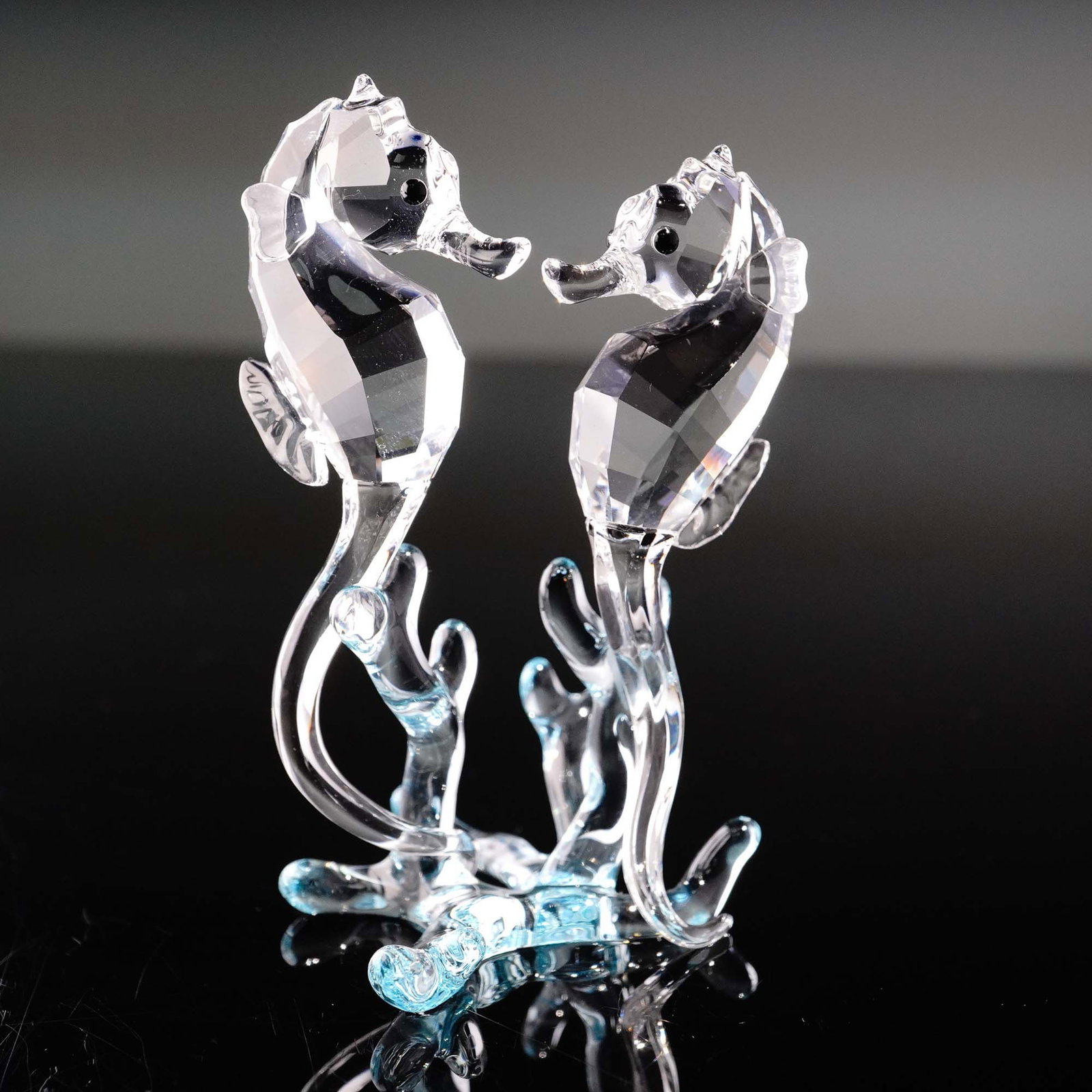Swarovski Crystal Figurine, Seahorses: This Swarovski crystal Seahorses figurine, item number 885589, features two faceted clear crystal seahorses gracefully posed on a wave-like base of blue-tinted crystal. The design captures an elegant 