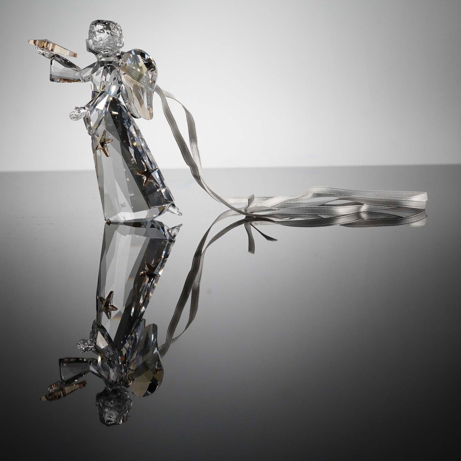 Swarovski Crystal Figurine, Angel Ornament 2010: This Swarovski Crystal Angel Ornament was released as part of the 2010 Annual Edition holiday collection. Crafted in clear crystal with golden accents and five delicate golden stars on her gown, the a