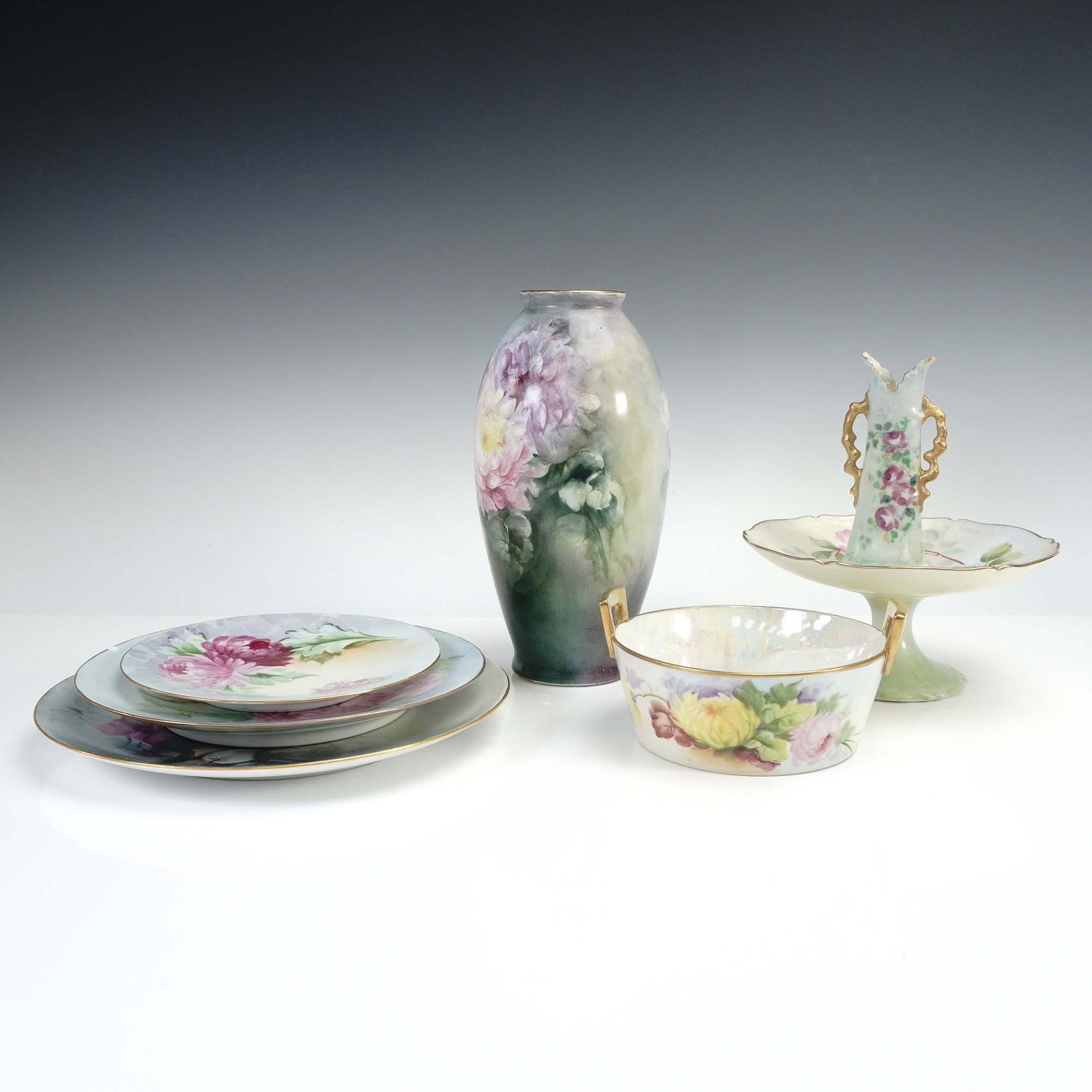 7pc Hand Painted Limoges Vases and Tableware: Collection of seven hand painted Limoges including three round plates of various size featuring large chrysanthemum and rose blooms, one tall floral vase, one reticulated handled bowl, one pedestal co