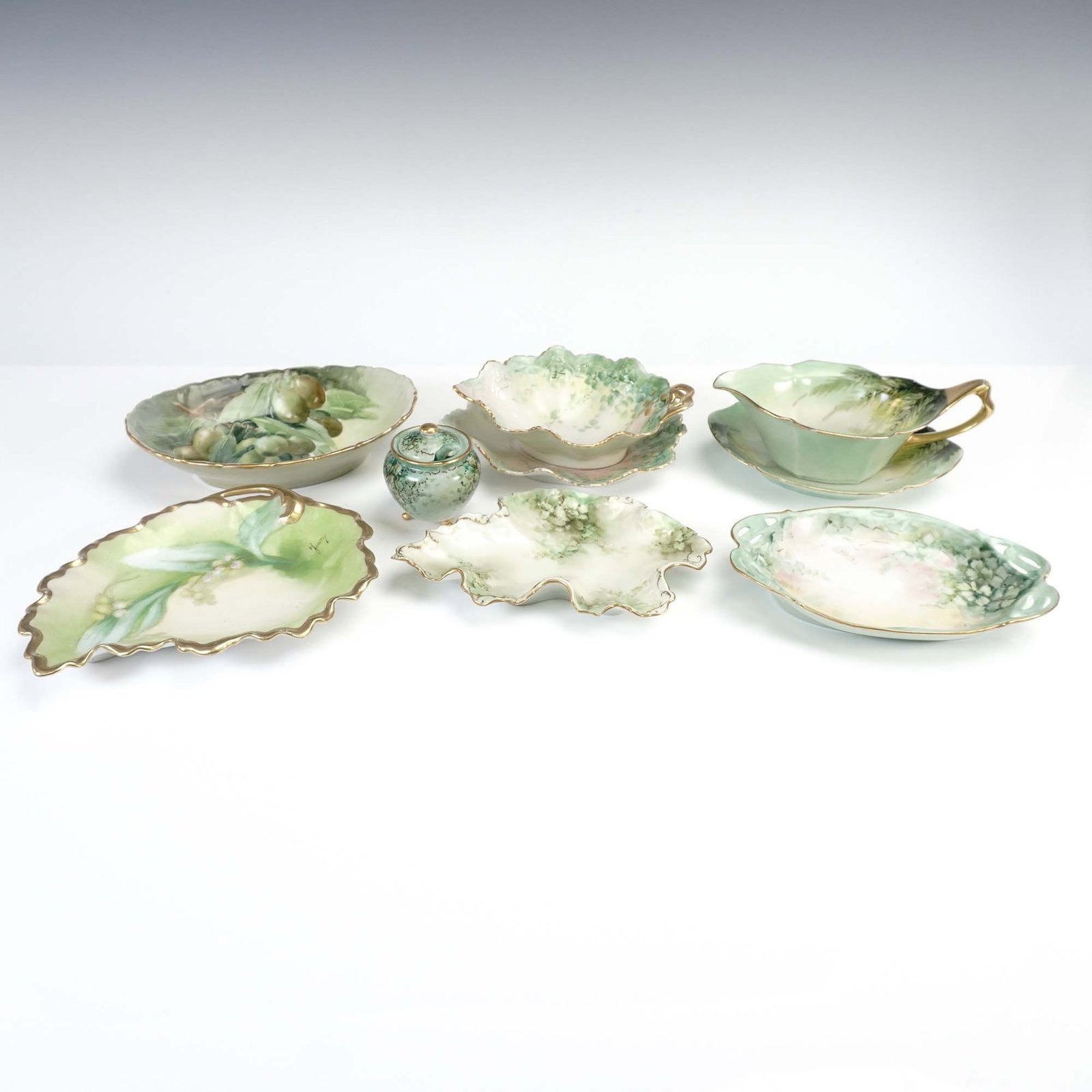 9pc Hand Painted Green Limoges Serve Ware: Collection of nine hand painted green serve ware items, including an assortment of shaped bowls and dishes, each decorated with floral or fruit motifs in green and white hues, with highlights of pink,