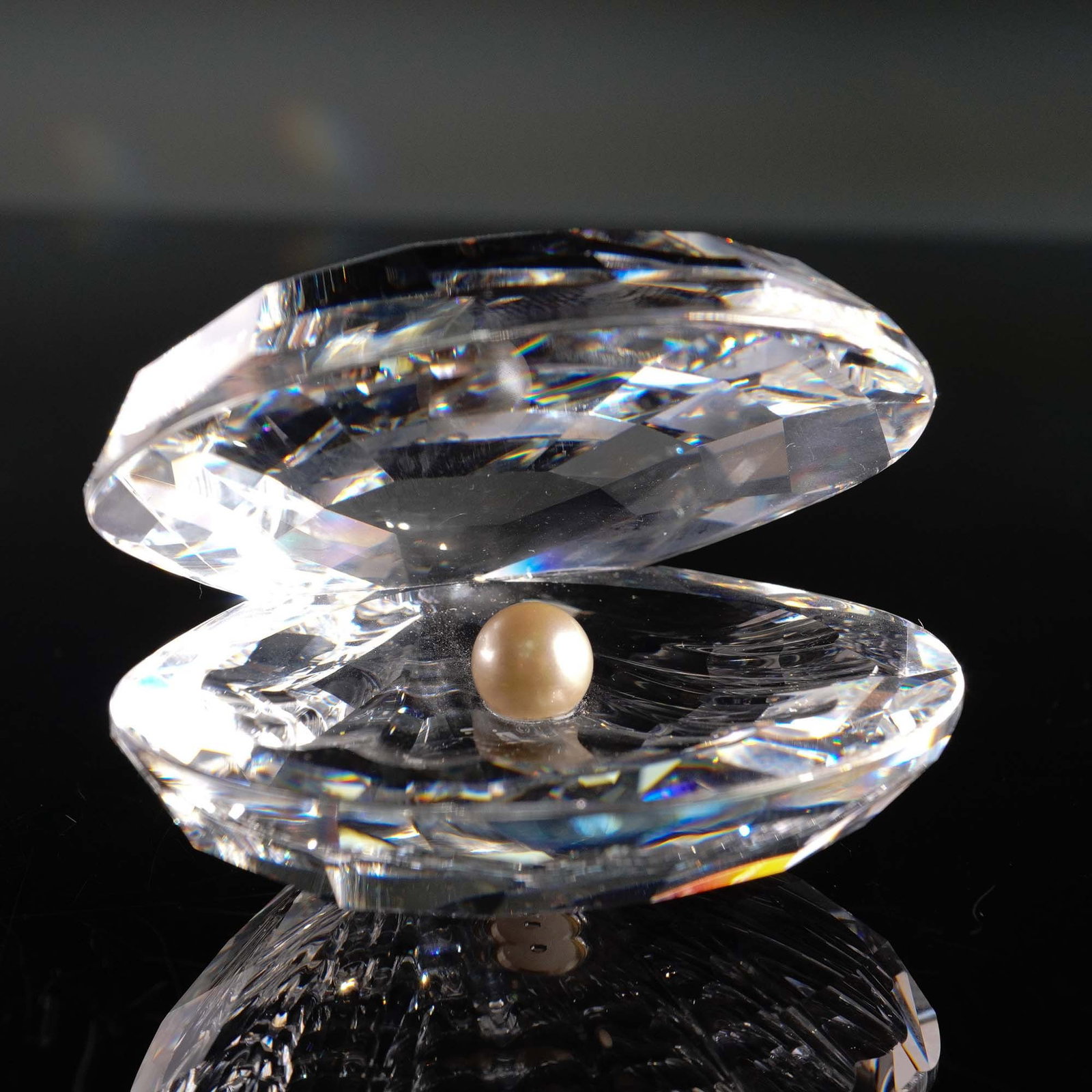 Swarovski Crystal Figurine, Clam with Pearl: This exquisite Swarovski Crystal figurine features a clam shell delicately crafted in faceted clear crystal, showcasing a shimmering pearl nestled within. The figurine is part of the renowned Swarovsk