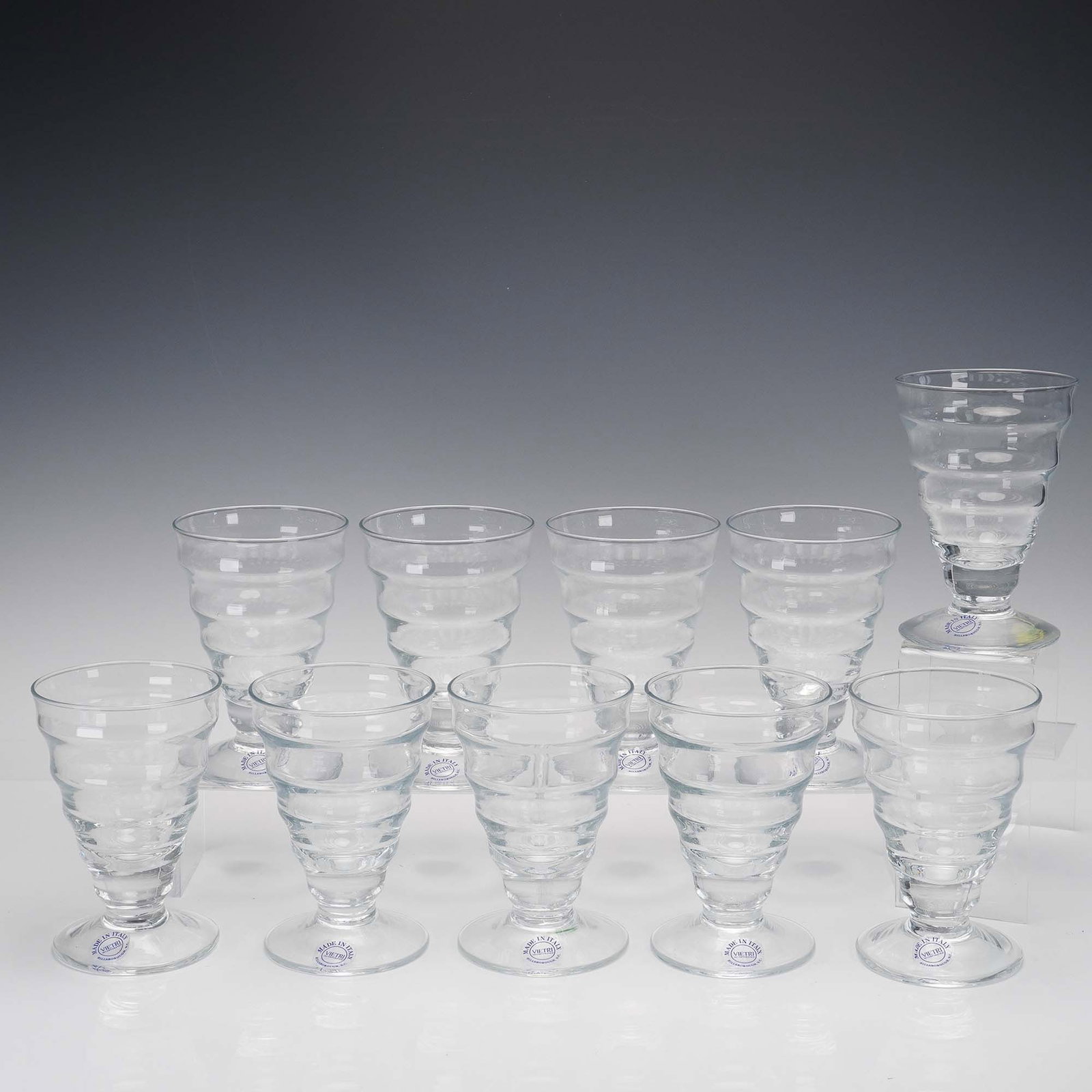 10pc Vietri Clear Glass Tumblers: This 10-piece set of Vietri clear glass tumblers showcases a distinctive, tiered design that creates a rippling visual effect. Each piece is crafted in Italy and bears the original sticker on the base
