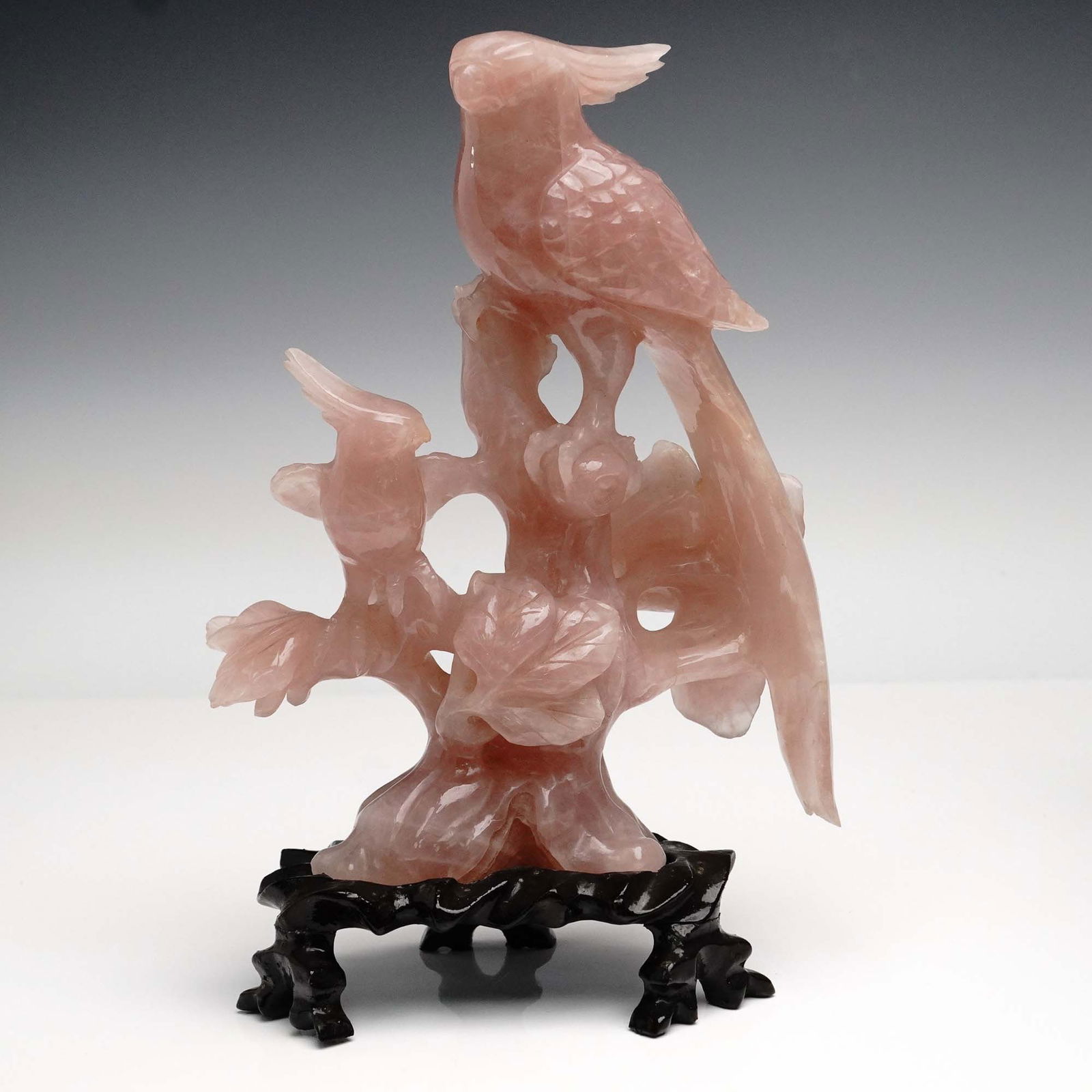 Chinese Rose Quartz Carved Bird Sculpture on Base: Intricately carved from a single piece of rose quartz, this delicate sculpture features a trio of birds perched on a stylized flowering tree. The main bird, possibly a parrot or cockatoo, is prominent