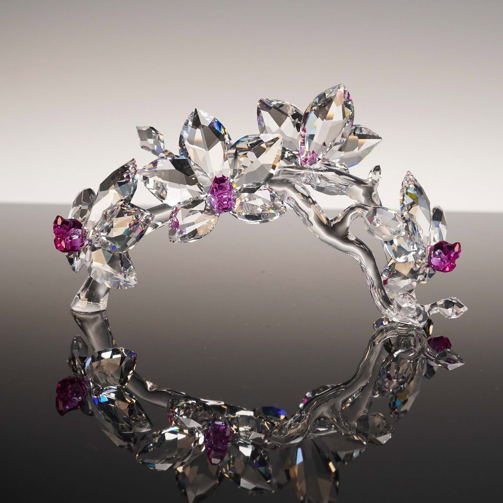 Swarovski Crystal Figurine, Orchid Pink with Dark Center: This stunning Swarovski crystal figurine features a graceful arched orchid branch adorned with large clear faceted blooms and vibrant dark pink centers. A beautiful representation of elegance and refi