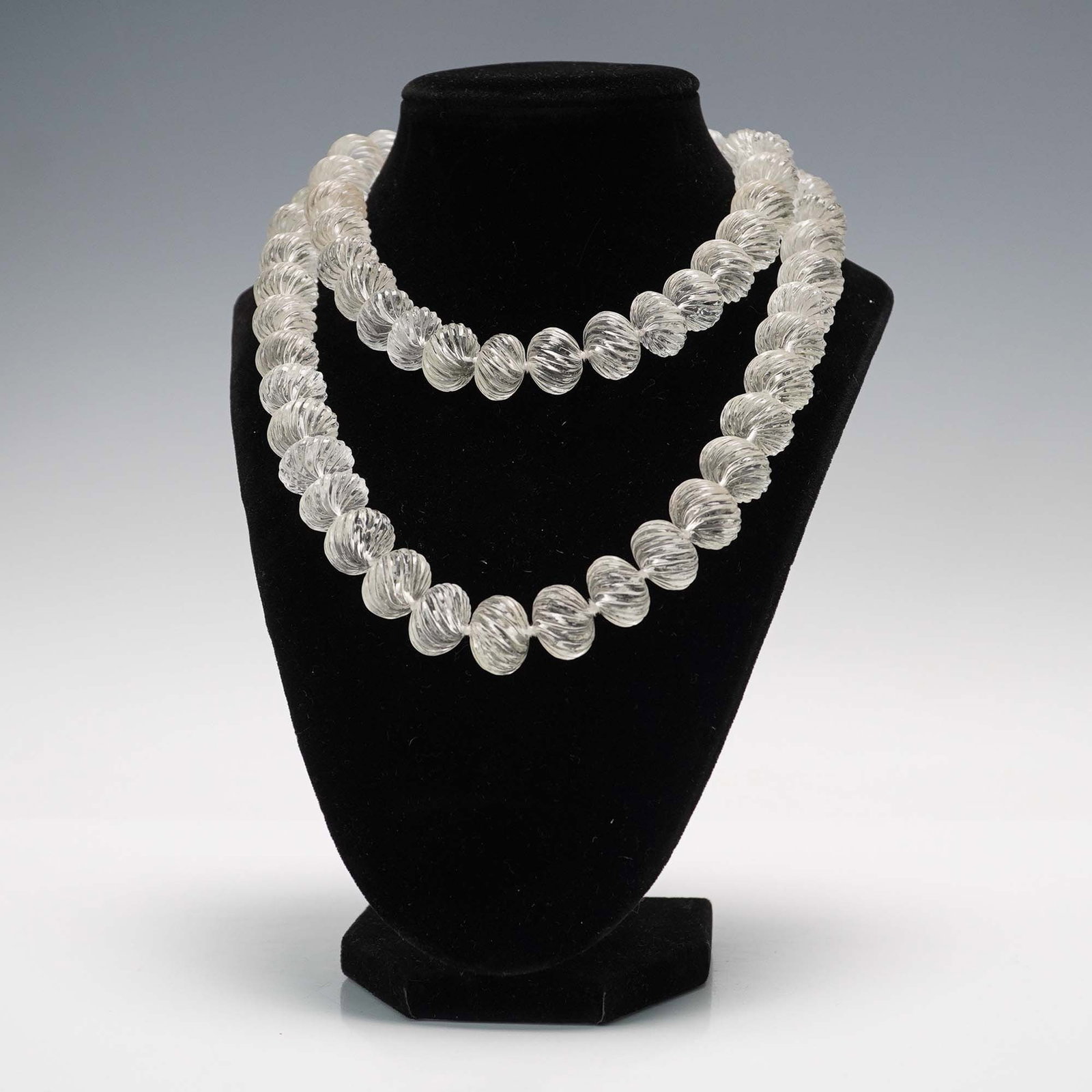 Venetian Glass Beaded Necklace: Strand of clear Venetian glass beads featuring a spiral-ribbed melon form, strung in a continuous loop. The beads are uniformly shaped and exhibit traditional Murano-style craftsmanship with optic rib