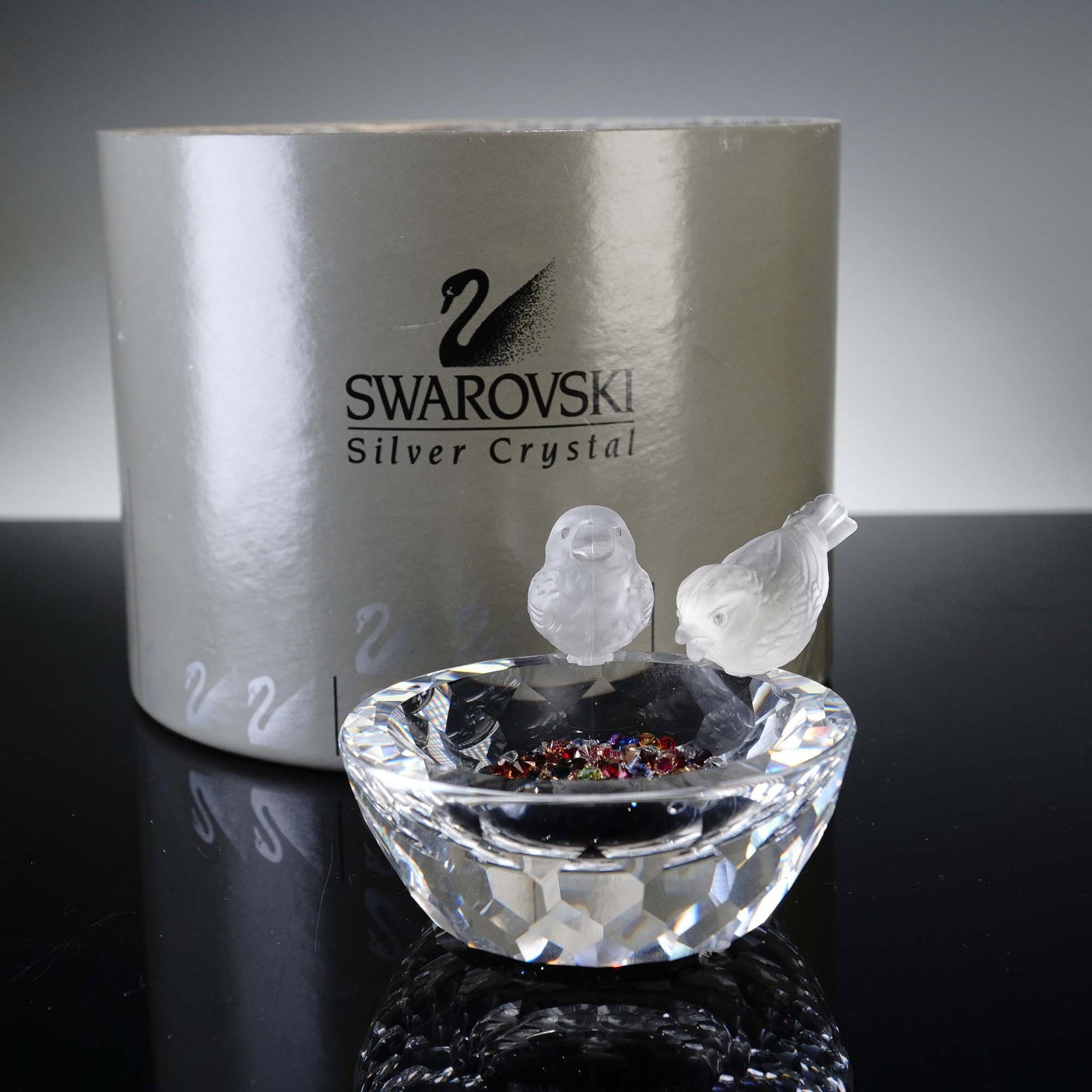 Swarovski Crystal Figurine, Bird Bath: Charming Swarovski Silver Crystal figurine titled "Bird Bath," featuring two frosted crystal birds perched gracefully on the edge of a meticulously faceted crystal bowl. The birds, with their delicate