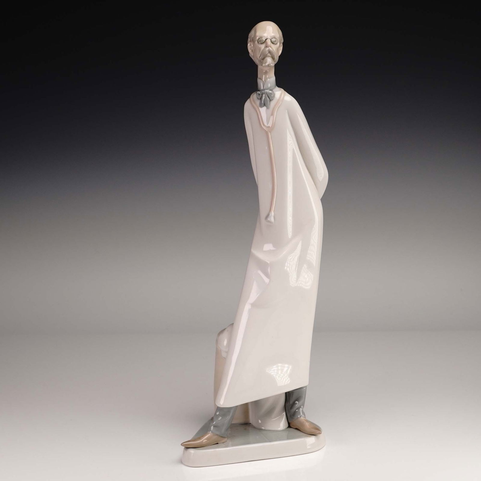 Lladro Porcelain Figurine, Doctor 01004602: Lladro porcelain figurine 01004602, titled Doctor, depicts a dignified elderly physician standing in a thoughtful pose with hands behind his back and spectacles perched on his nose. Sculpted by renown