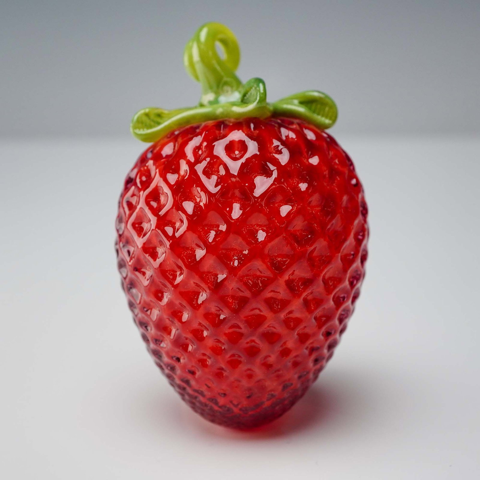 Art Glass Figurine, Strawberry Fruit Paperweight: This vibrant strawberry art glass paperweight is a playful and realistic decorative piece handcrafted by artisans from Artful Home. Featuring a lifelike textured red body and a translucent green leafy