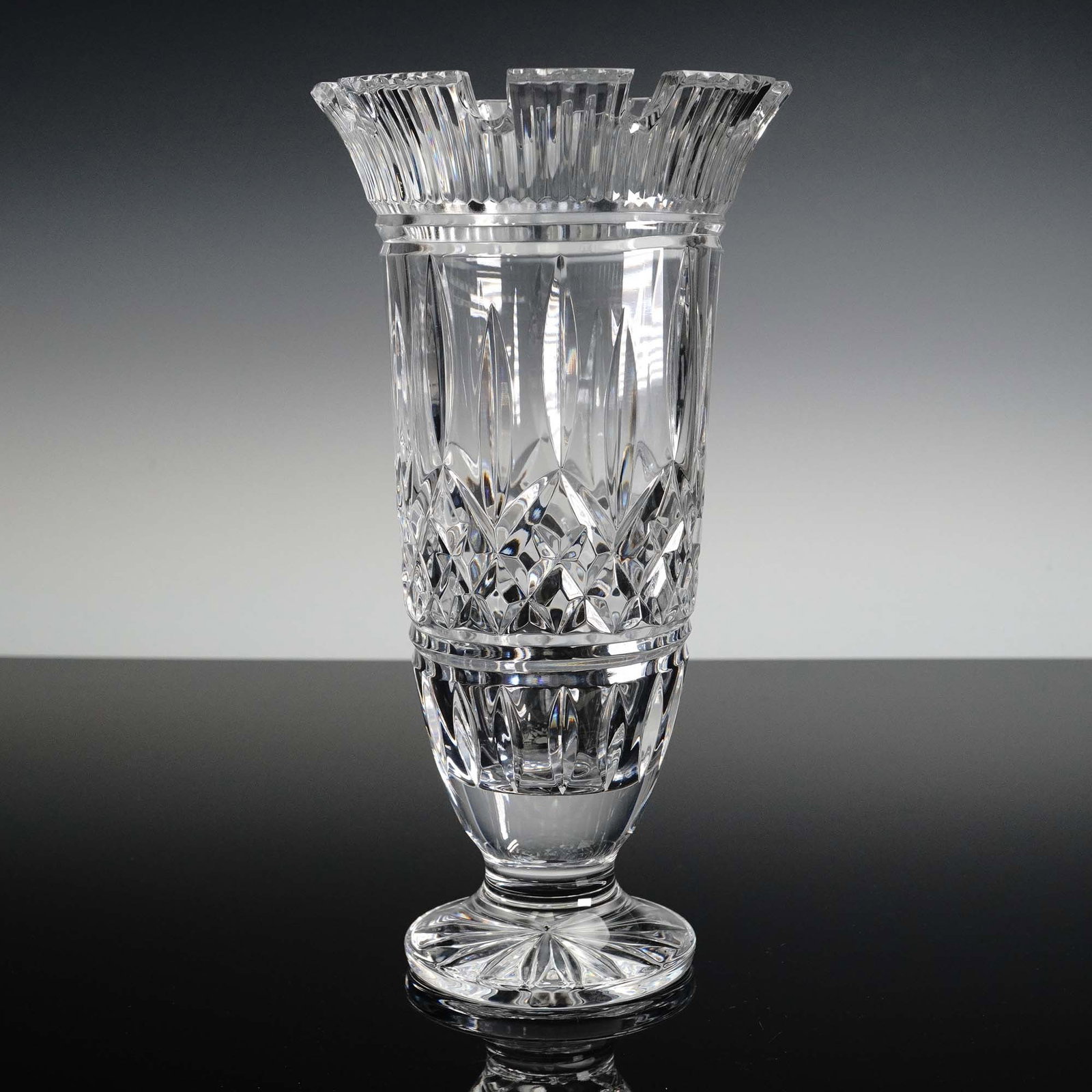 Waterford Crystal Footed Vase with Flared Rim: This striking Waterford crystal vase features the brand's iconic brilliance and masterful cutwork, with deep crisscross and elongated vertical cuts adorning its body, tapering into a finely faceted pe