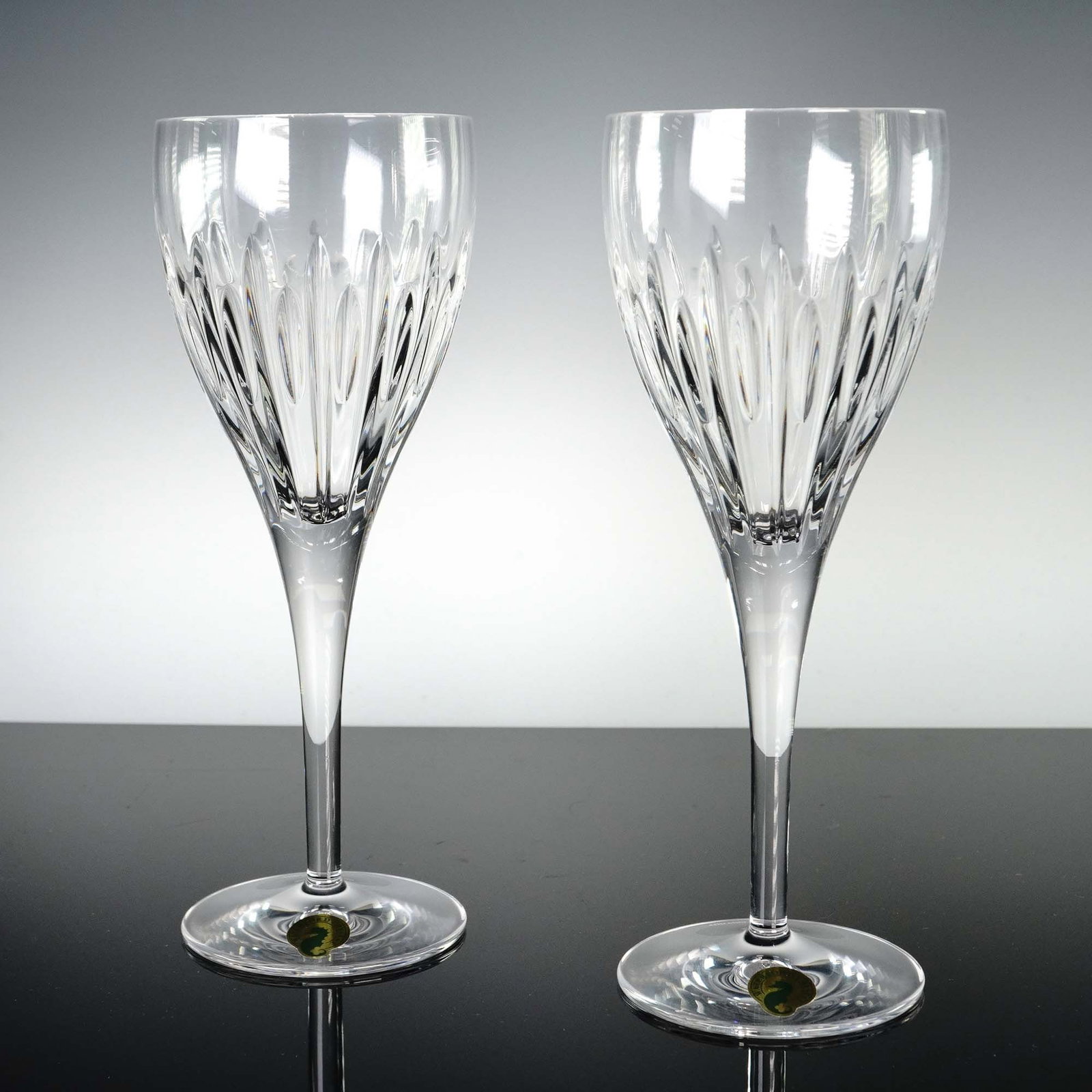 2pc Waterford Crystal Enis Wine Glasses 9H: This 2-piece set of Waterford Crystal Enis Wine Glasses features a graceful tulip bowl with elegant vertical and crisscross cut patterns rising from the base, creating a striking visual play of light 