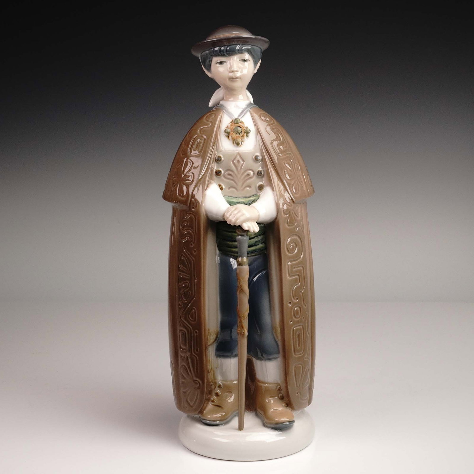 Lladro Porcelain Figurine, Little Town Mayor 1001161: Issued in 1971 and sculpted by Julio Fernández, Little Town Mayor is a charming representation of Lladro's early porcelain artistry. This finely detailed figurine portrays a youthful mayor standing p