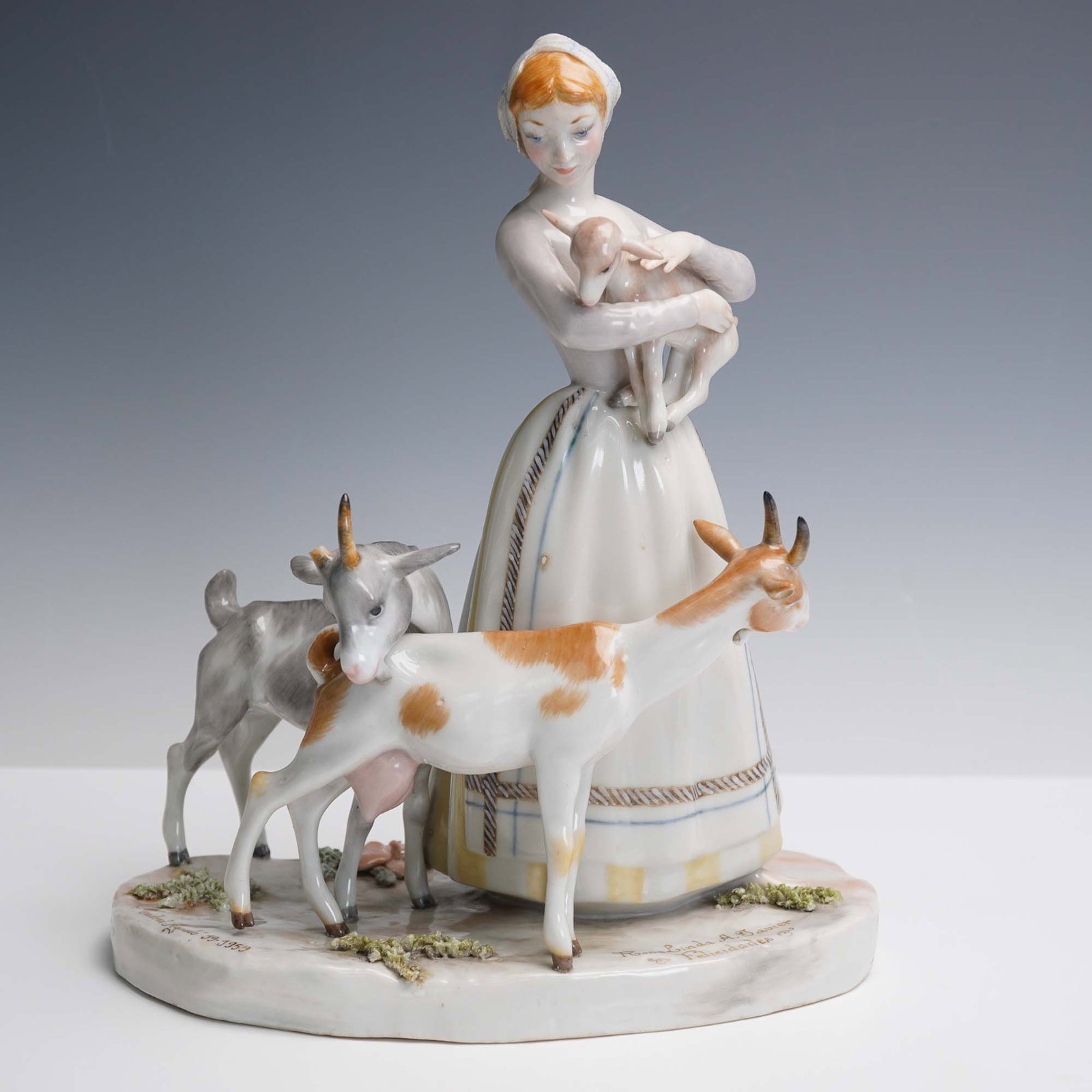 Lladro Porcelain Figurine, Shepherdess with Goats 1001001: This delicate Lladro porcelain figurine depicts a shepherdess tenderly holding a fawn while two goats graze at her feet. The piece is hand-inscribed Lladro on the underside and dated Madrid Agosto 19 