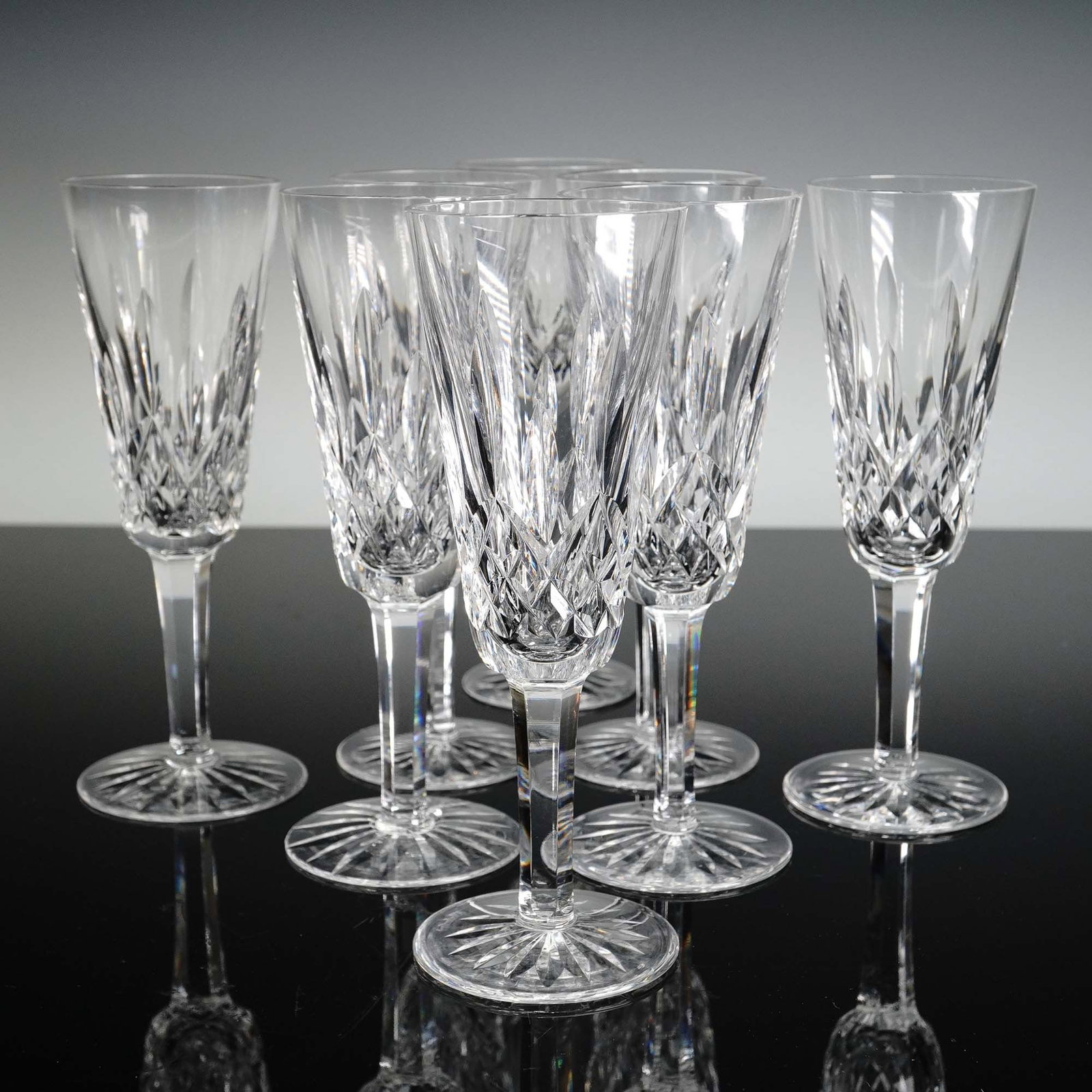 8pc Waterford Crystal Fluted Champagne Glasses, Lismore: Set of eight Waterford crystal fluted champagne glasses in the Lismore pattern. Each glass features the classic vertical and crisscross cut design synonymous with the Lismore line, known for its brill