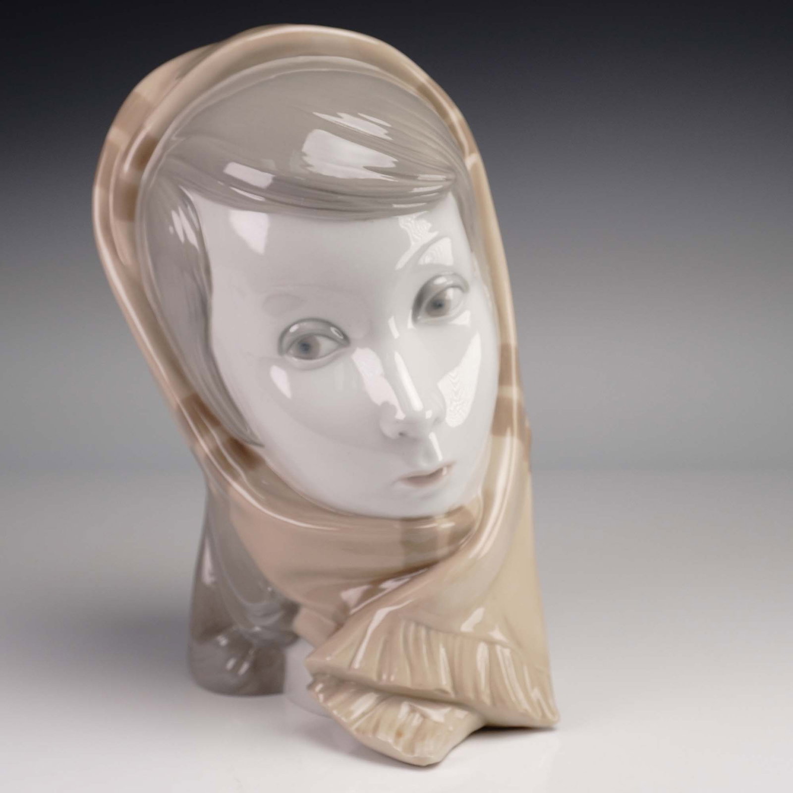 Lladro Porcelain Girl's Head Bust PP140a: Lovely creation of young girl's head, colored in soft tan and gray tones. Lladro impressed mark on base. Artist: Vincente Martinez Issued: 1968 Dimensions: 9"H Country of Origin: Spain