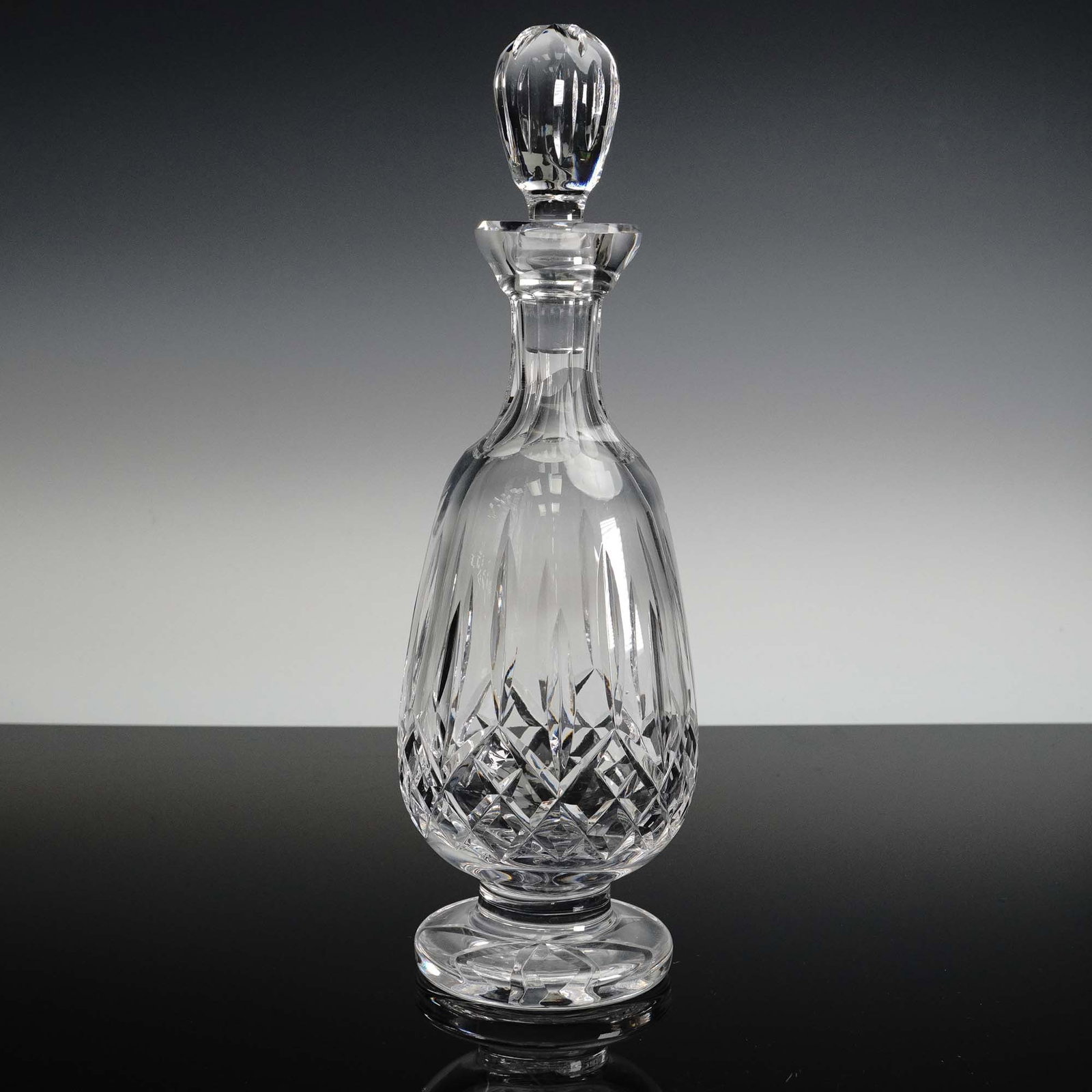 Waterford Crystal Footed Decanter with Stopper: Brilliantly crafted Waterford crystal decanter featuring an elegant footed base and a faceted teardrop-shaped stopper. This piece showcases the signature brilliance and craftsmanship of Waterford, wit