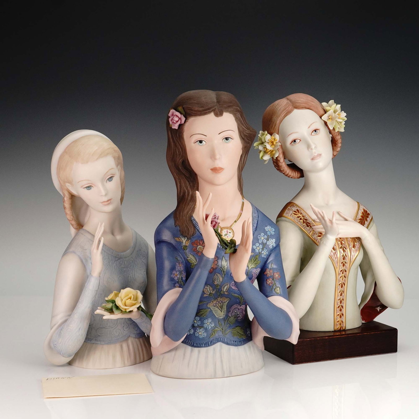 3pc Porcelain Bust Figurines, Cybis & Ispanky: Set of three hand-painted porcelain bust figurines by Cybis and Ispanky, each featuring delicate floral details and serene expressions. The Cybis piece is marked #654 and set on a wood base; the Ispan
