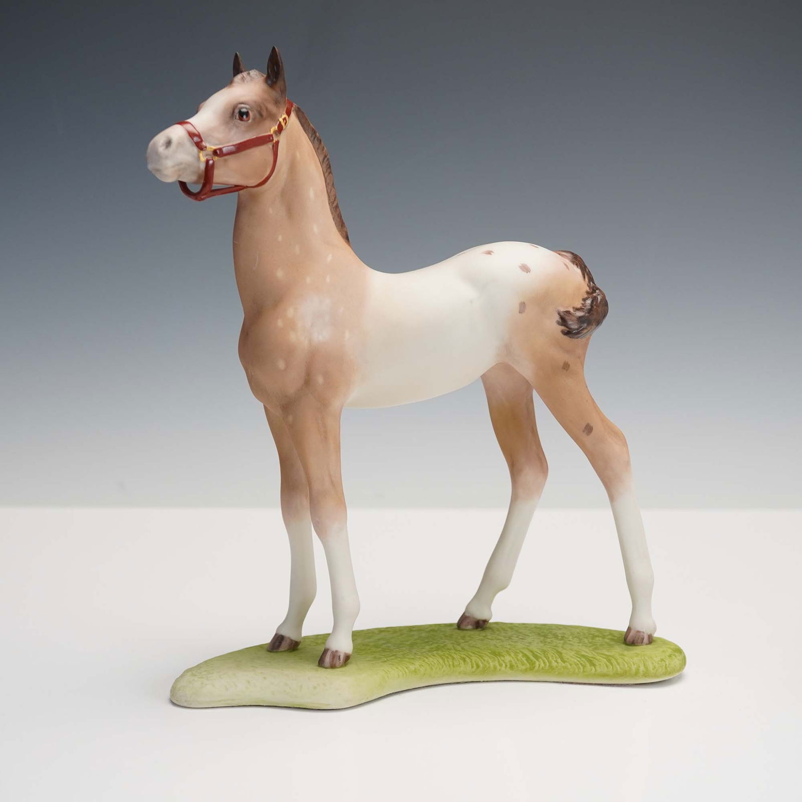 Cybis Porcelain Figurine, Appaloosa Colt: This striking porcelain figurine by Cybis features a proud young Appaloosa colt, sculpted in a noble stance with its head held high. Rendered in matte bisque porcelain, the colt displays a warm coat w